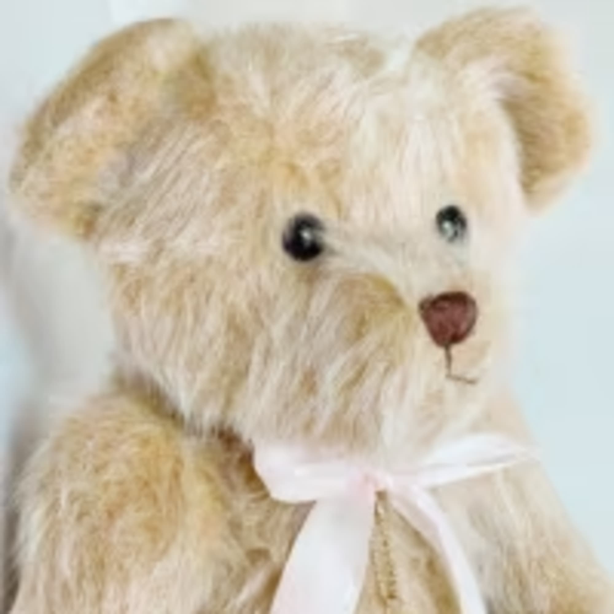 Plush teddy bear with a white ribbon bow
