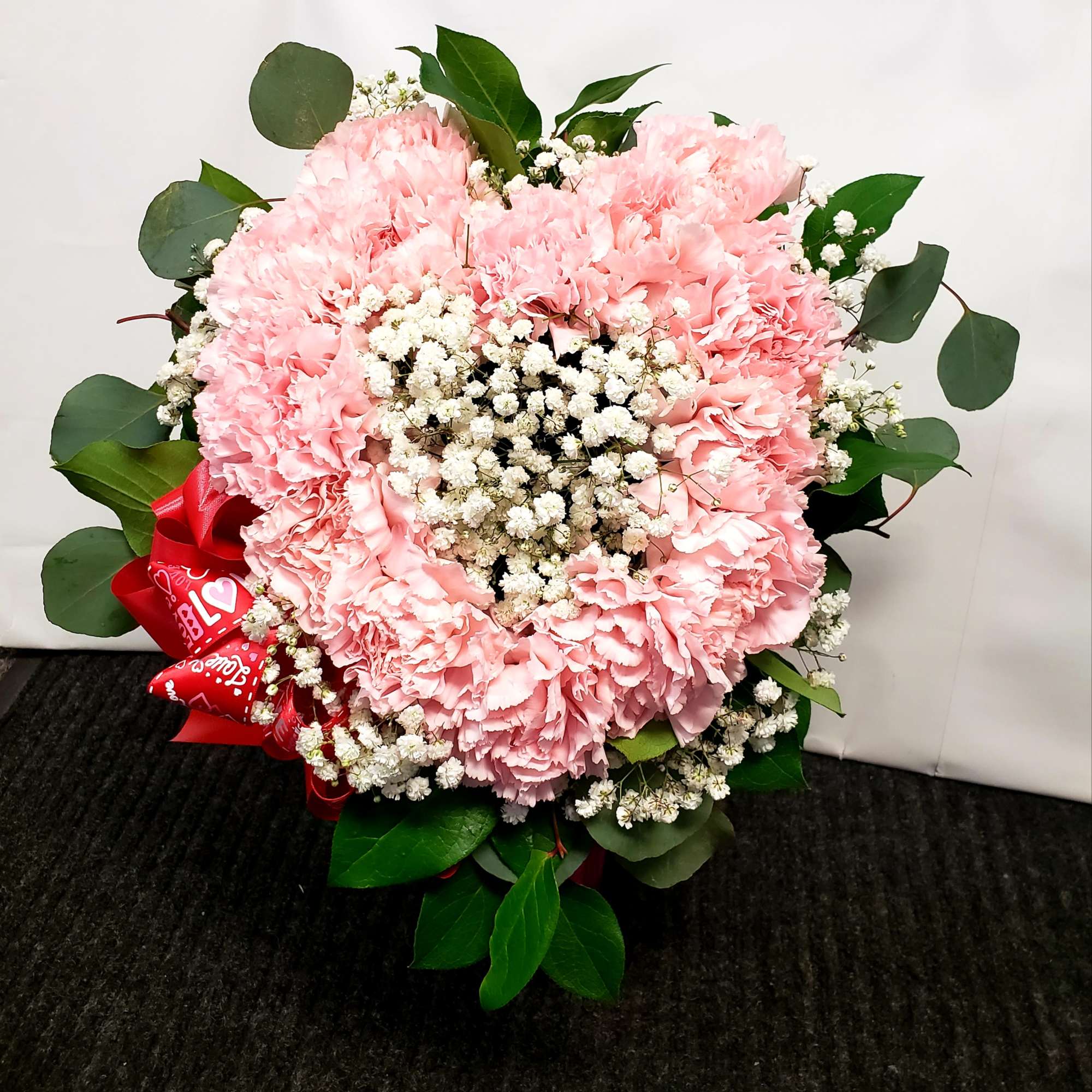 Pink carnation bouquet with baby's breath and a red ribbon