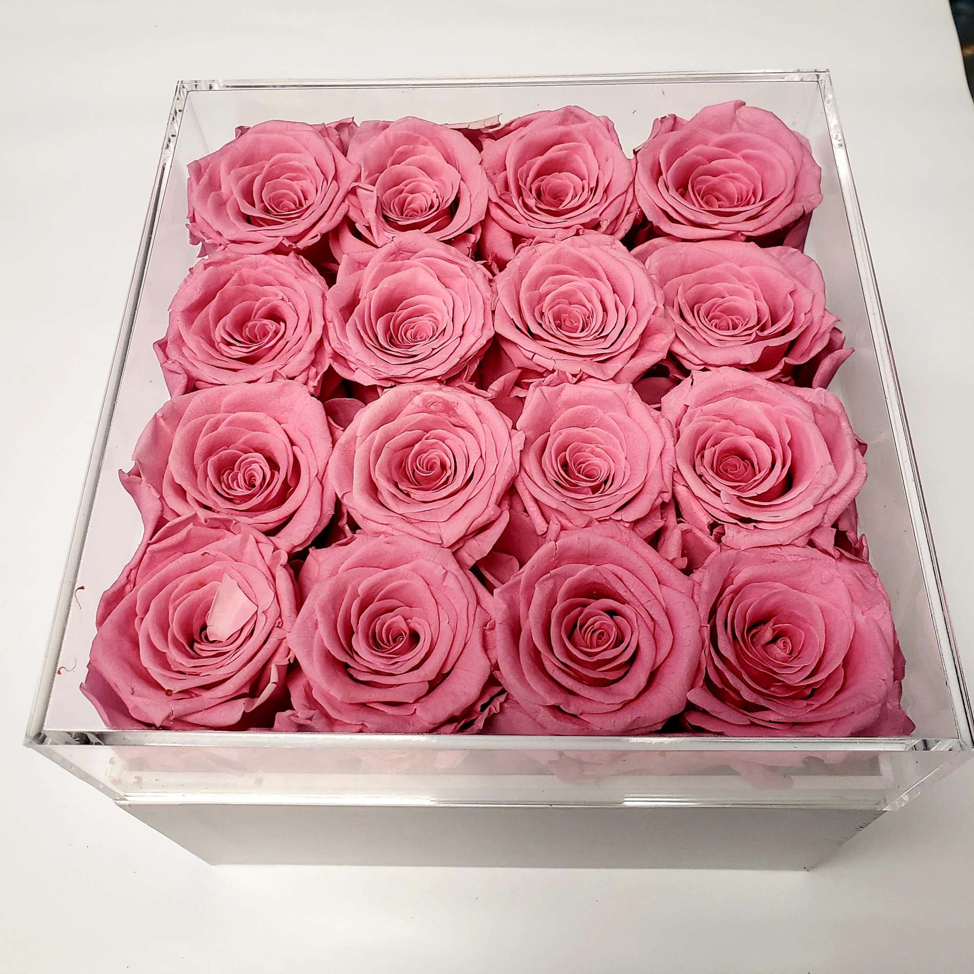 Box of pink roses arranged in a clear square container