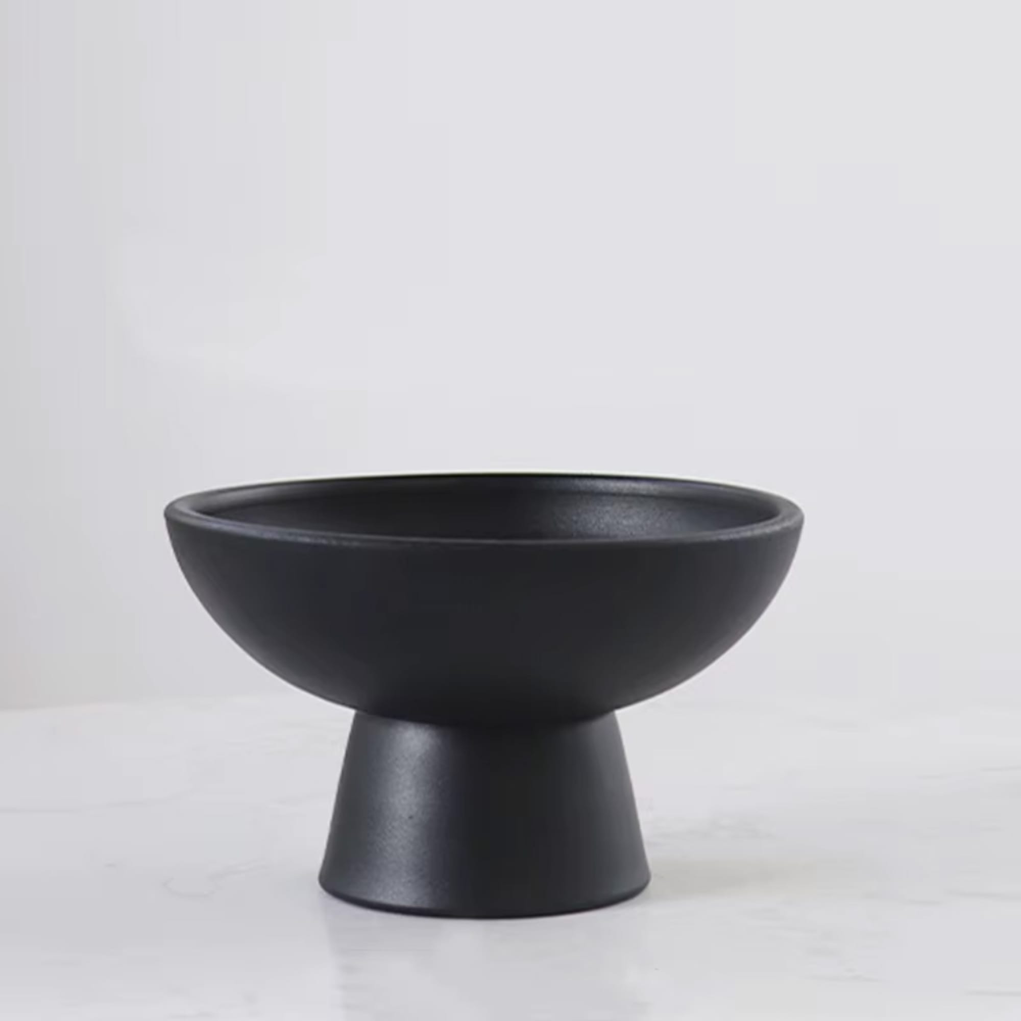 Black pedestal bowl vase on a white surface