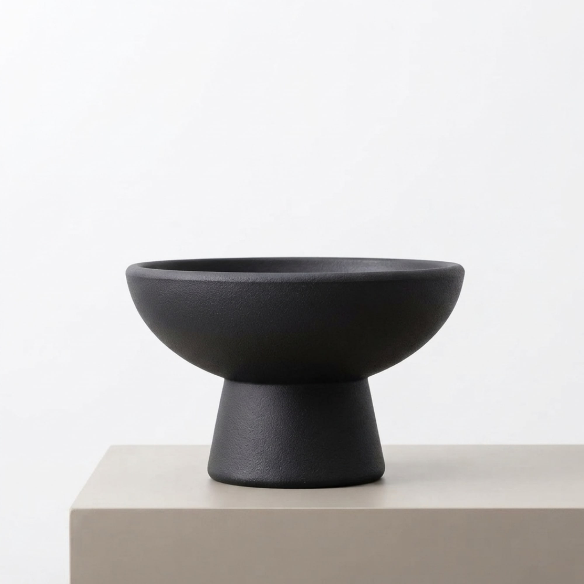 Black pedestal bowl on a light surface against a white background