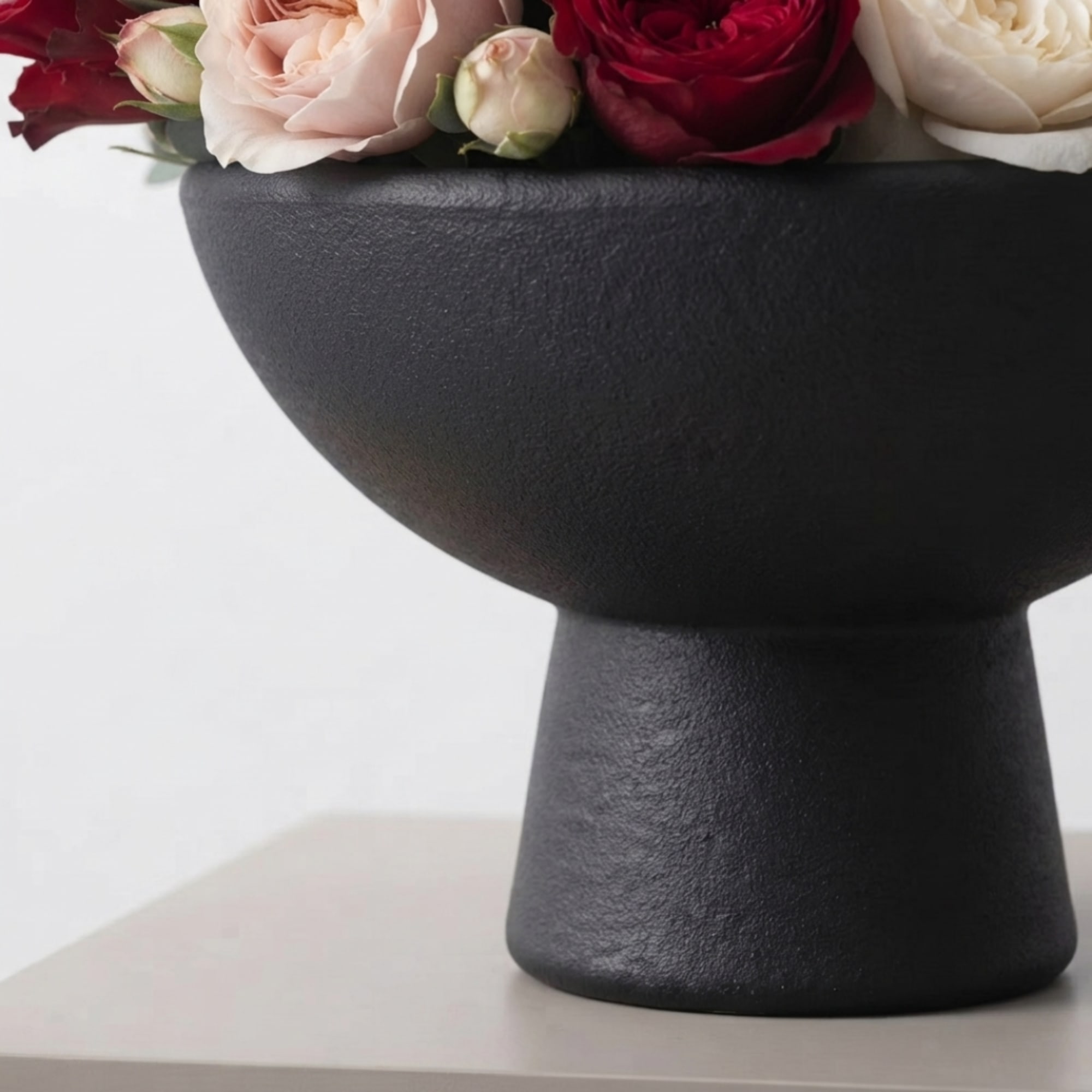 Pink and red roses in a black pedestal vase