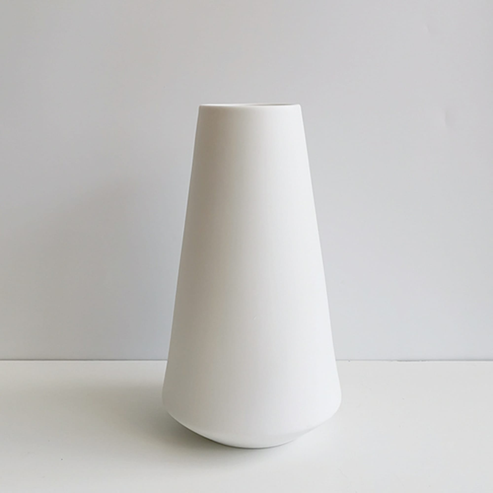 Tall white ceramic vase on a plain background
