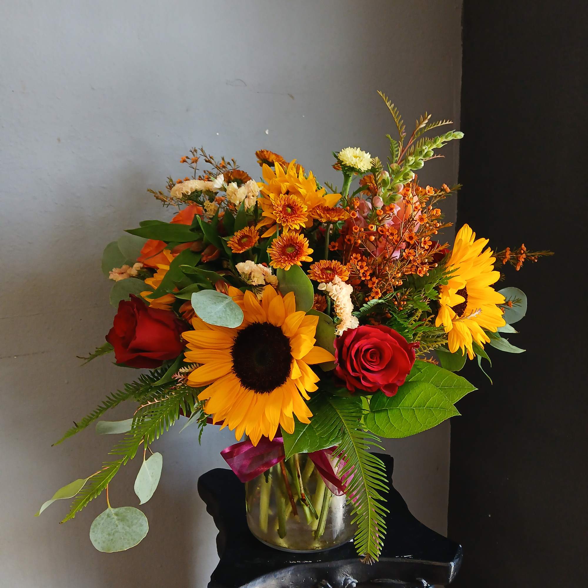 Bouquet of sunflowers and red roses in a glass vase