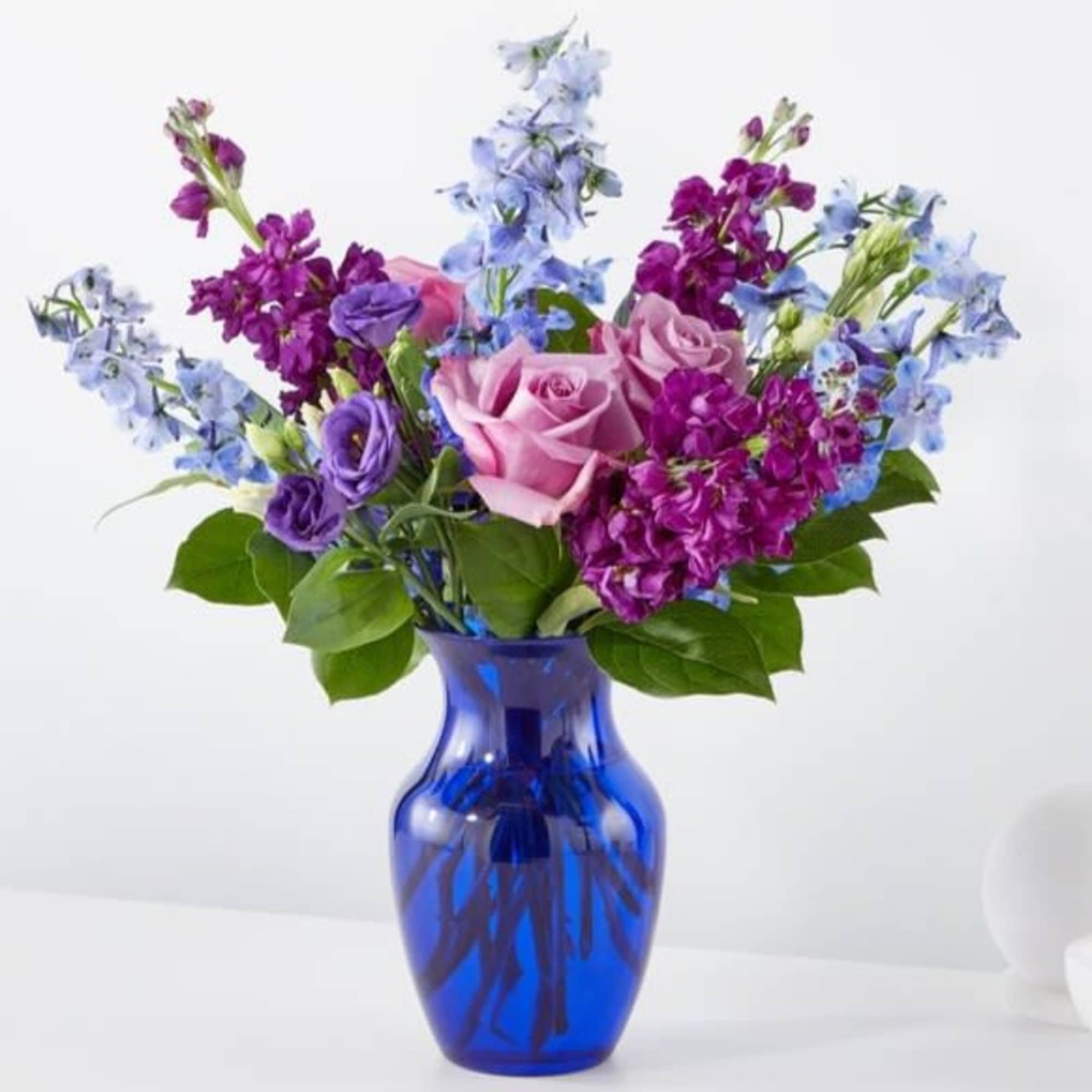 Pink and purple flowers arranged in a blue glass vase