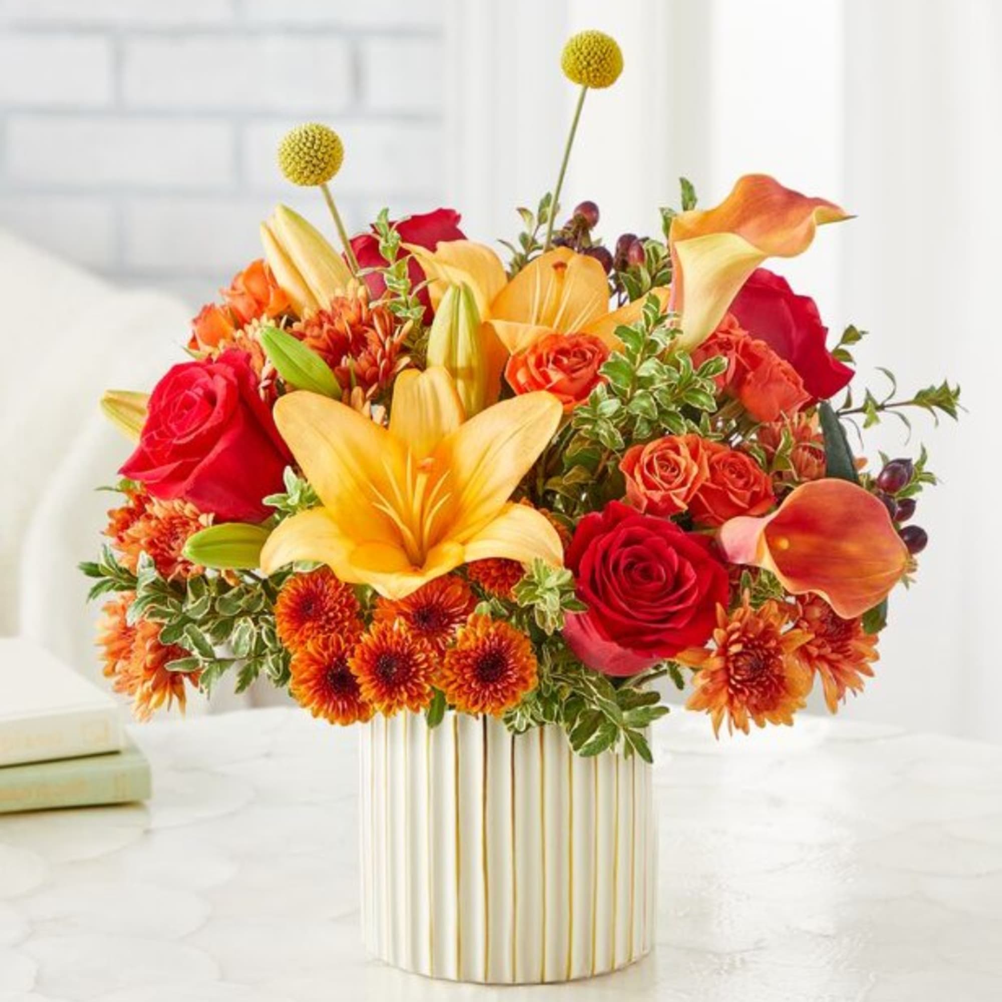 Colorful bouquet of roses, lilies, calla lilies, and mums in a striped vase