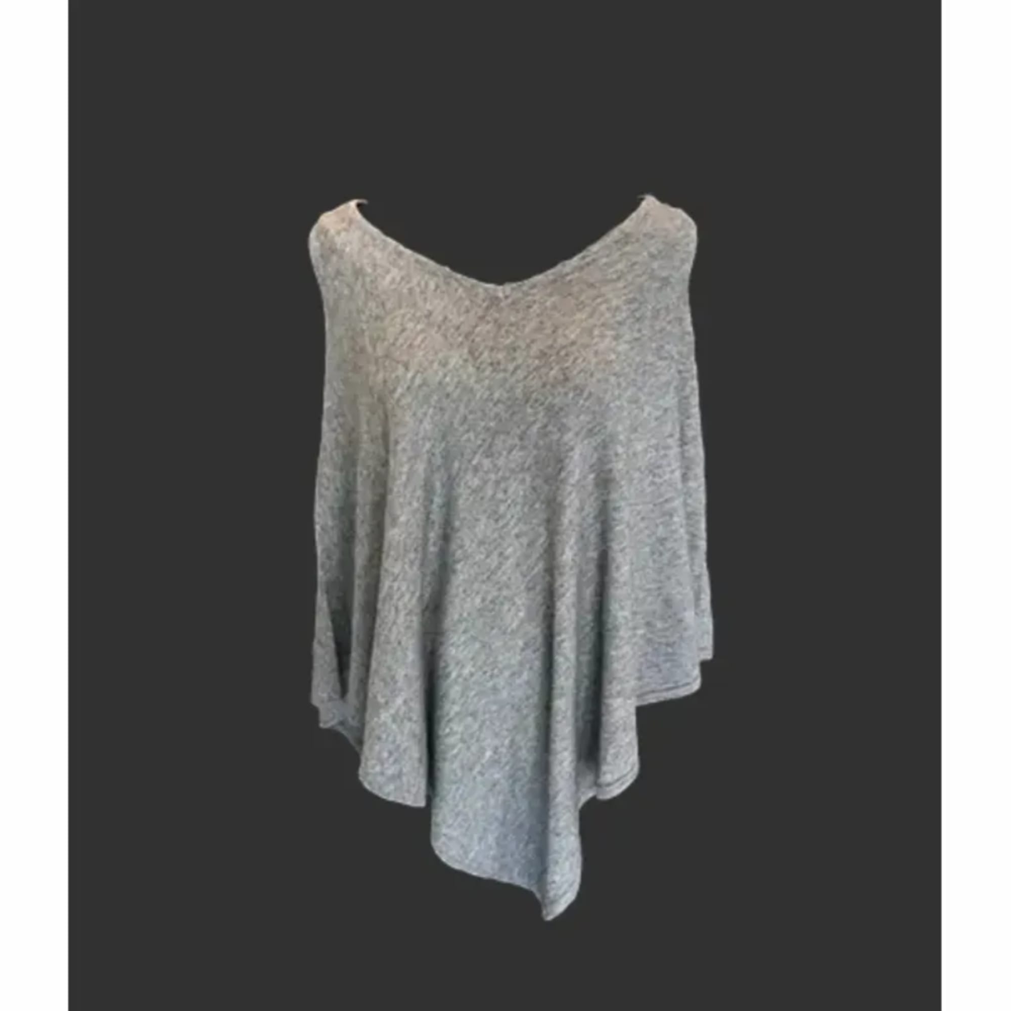 Gray knit poncho draped against a dark background