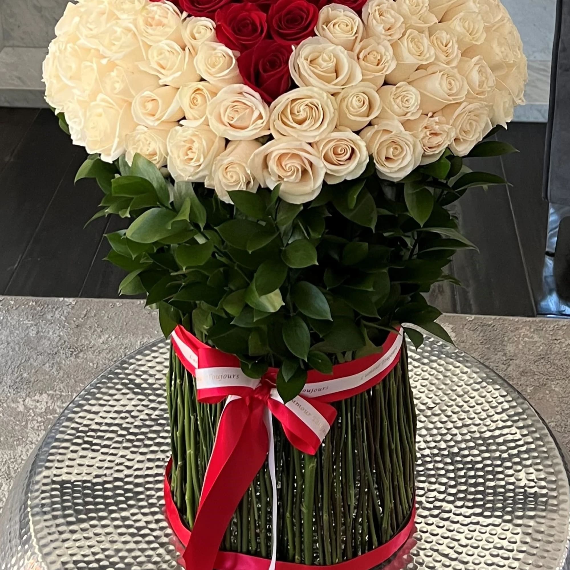 Round bouquet of red and white roses in a tall wrapped base