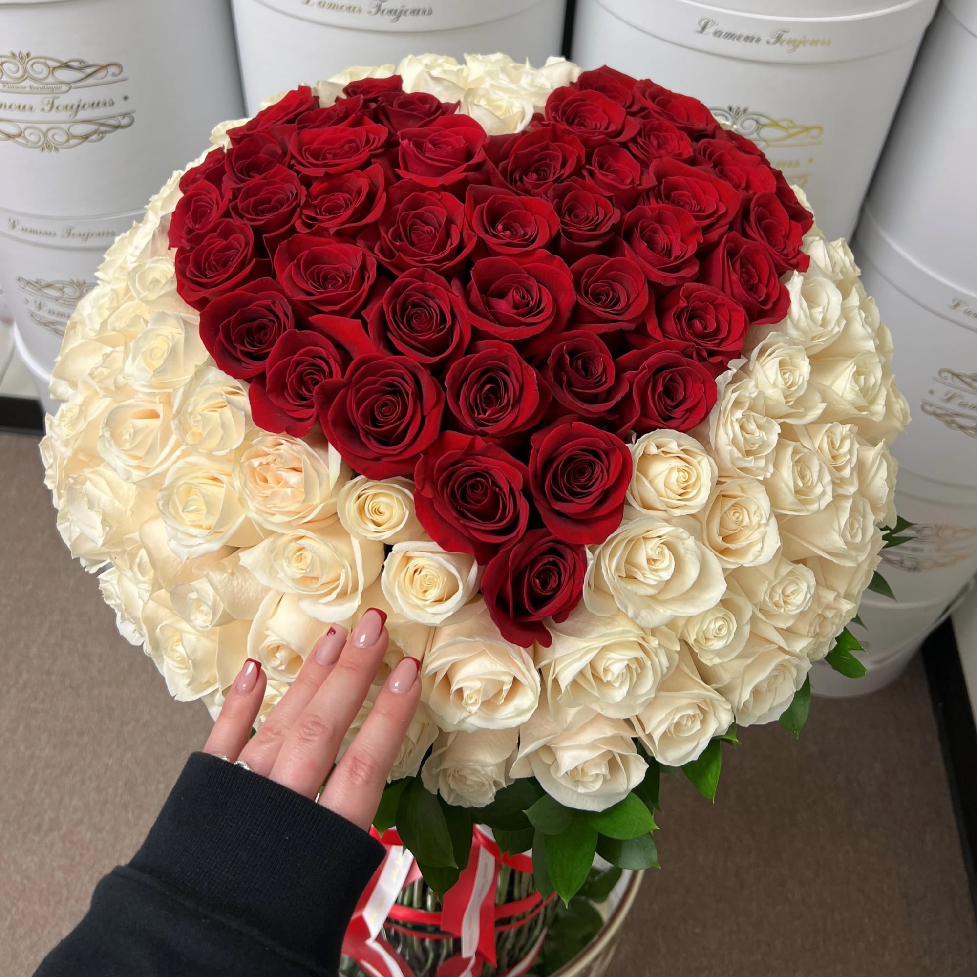 Heart-shaped bouquet of red and white roses in a round box