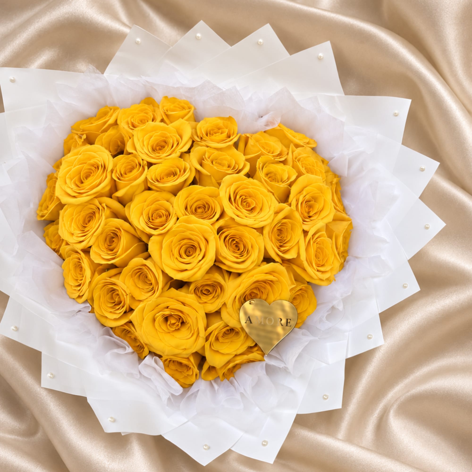 Yellow rose bouquet wrapped in white paper with a gold heart tag