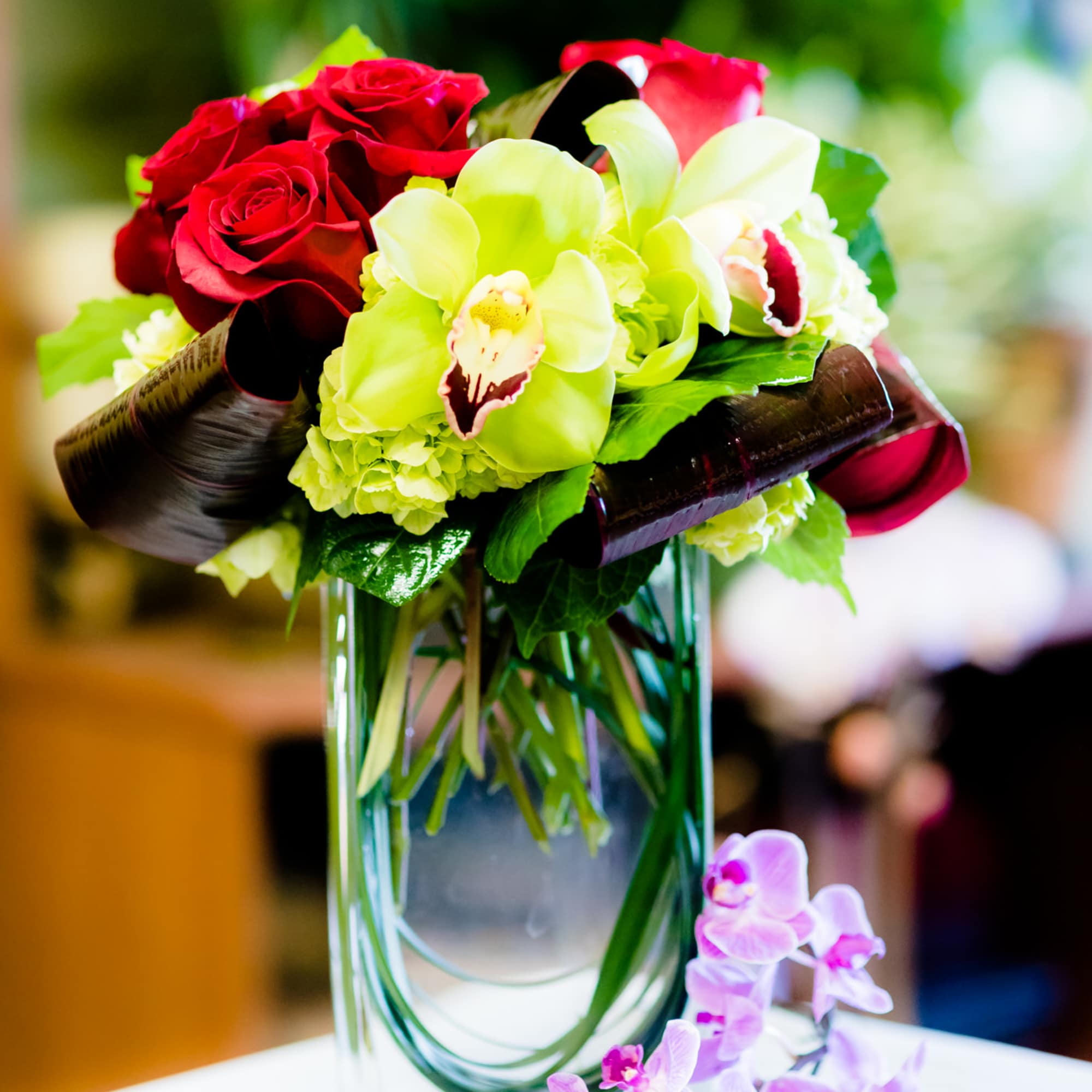Bouquet of red roses and green orchids in a glass vase