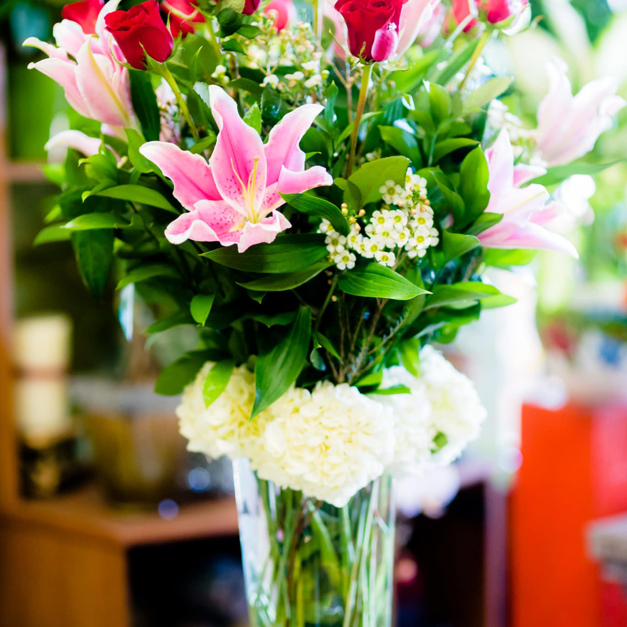 Bouquet of pink lilies and red roses in a clear glass vase