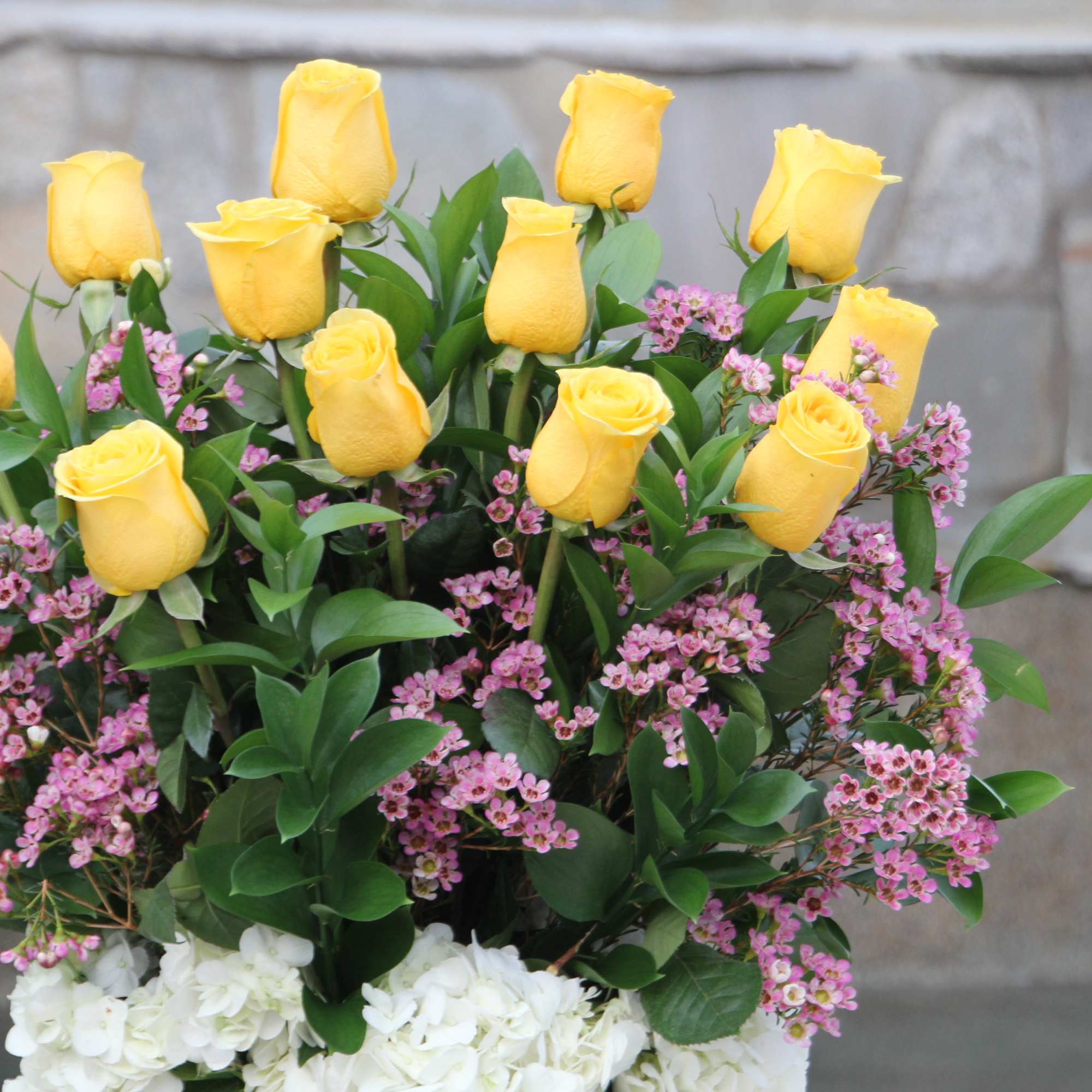 Yellow roses with pink filler flowers and white hydrangeas