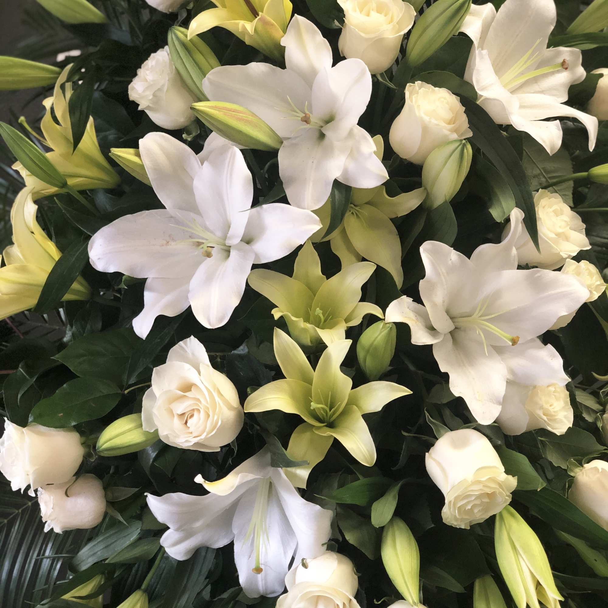 White lilies and cream roses arranged in a dense bouquet