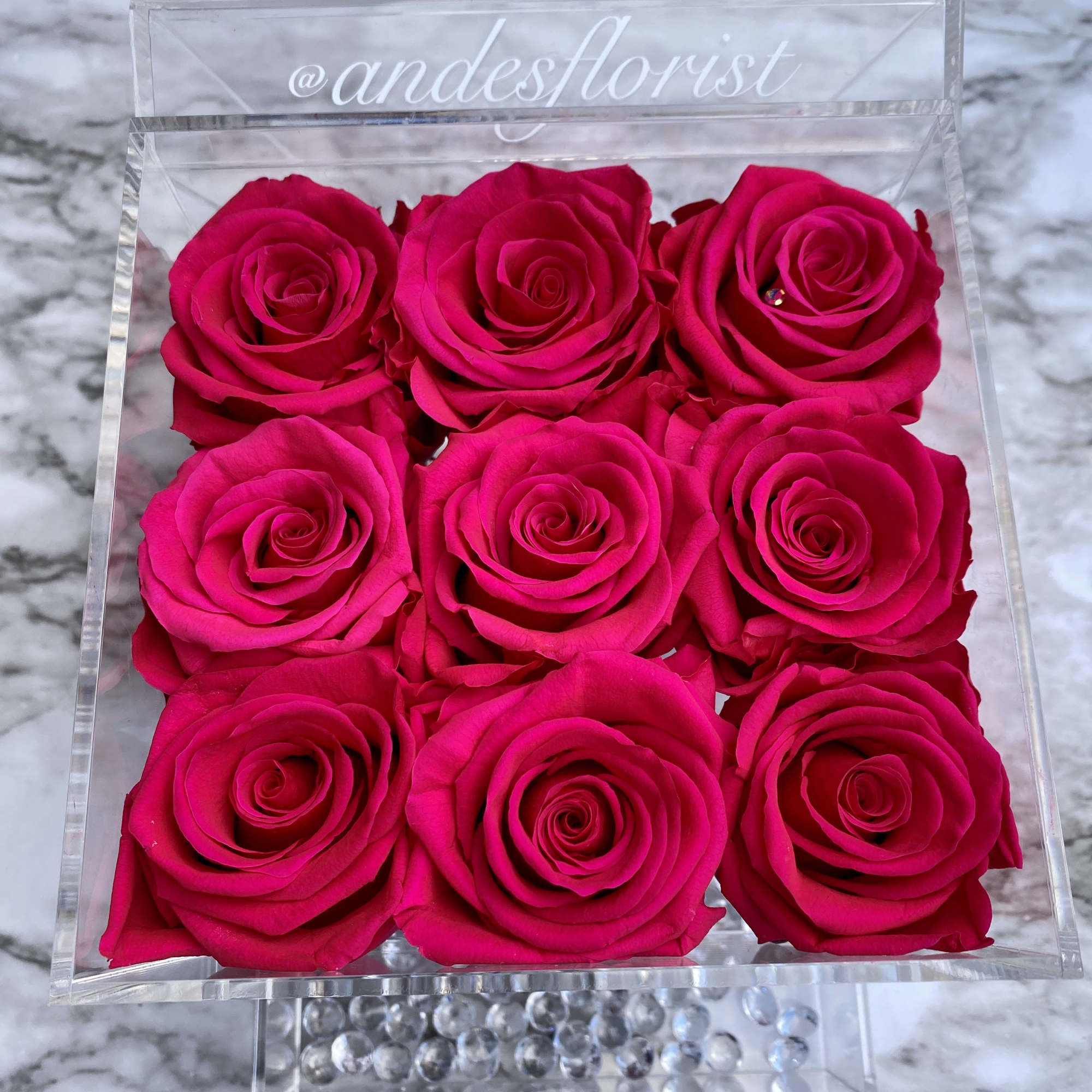 Nine hot pink roses in a clear square box