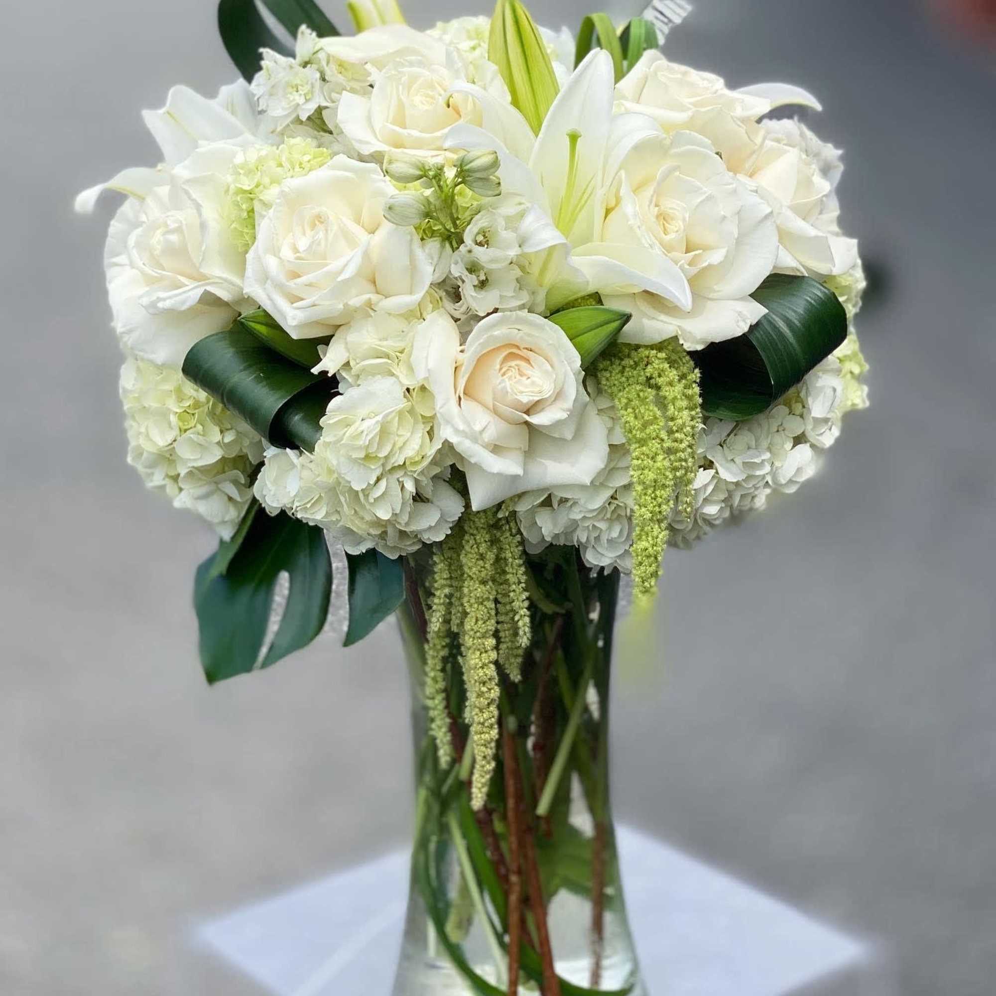 White roses and lilies arranged in a clear glass vase