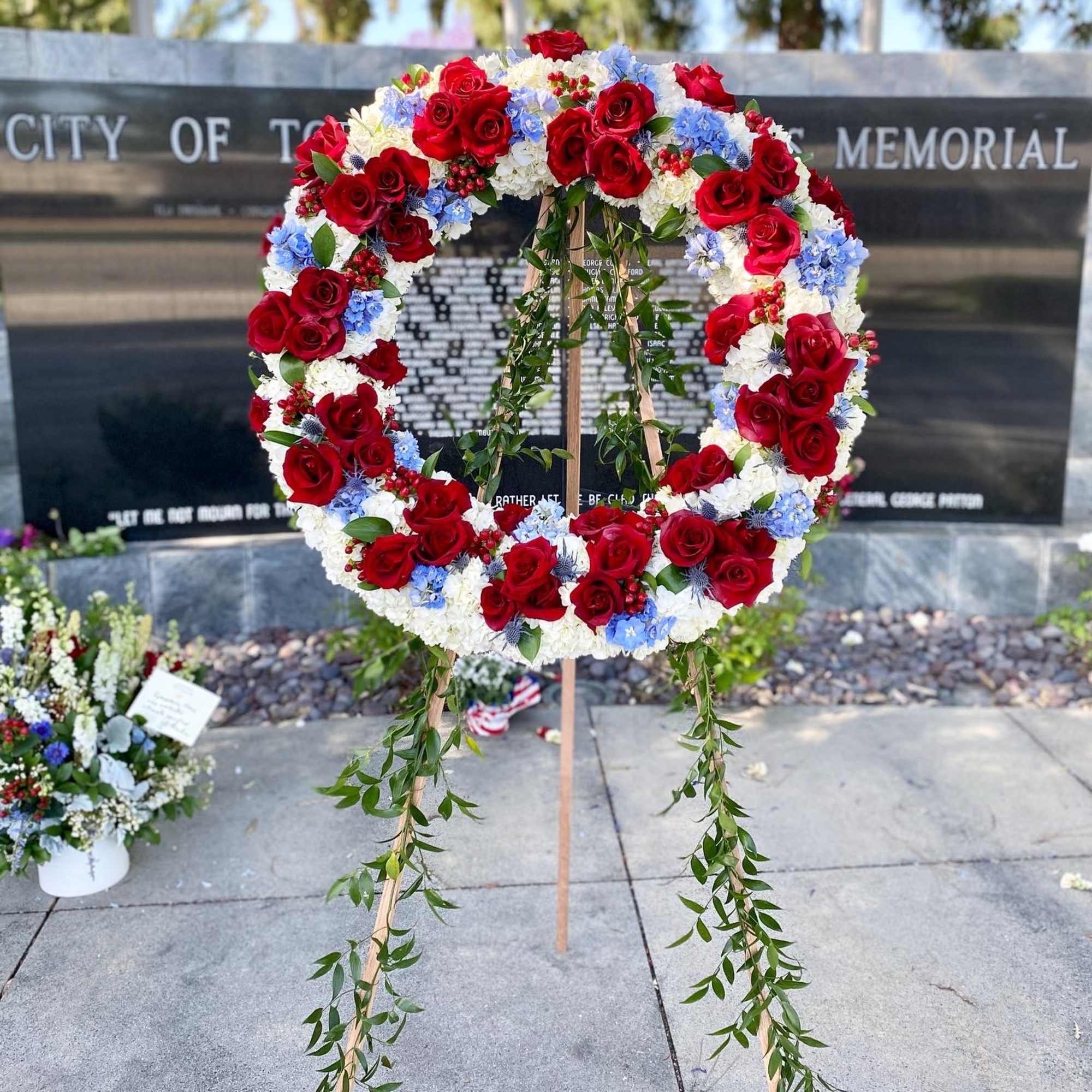 Large red, white, and blue floral wreath on a stand