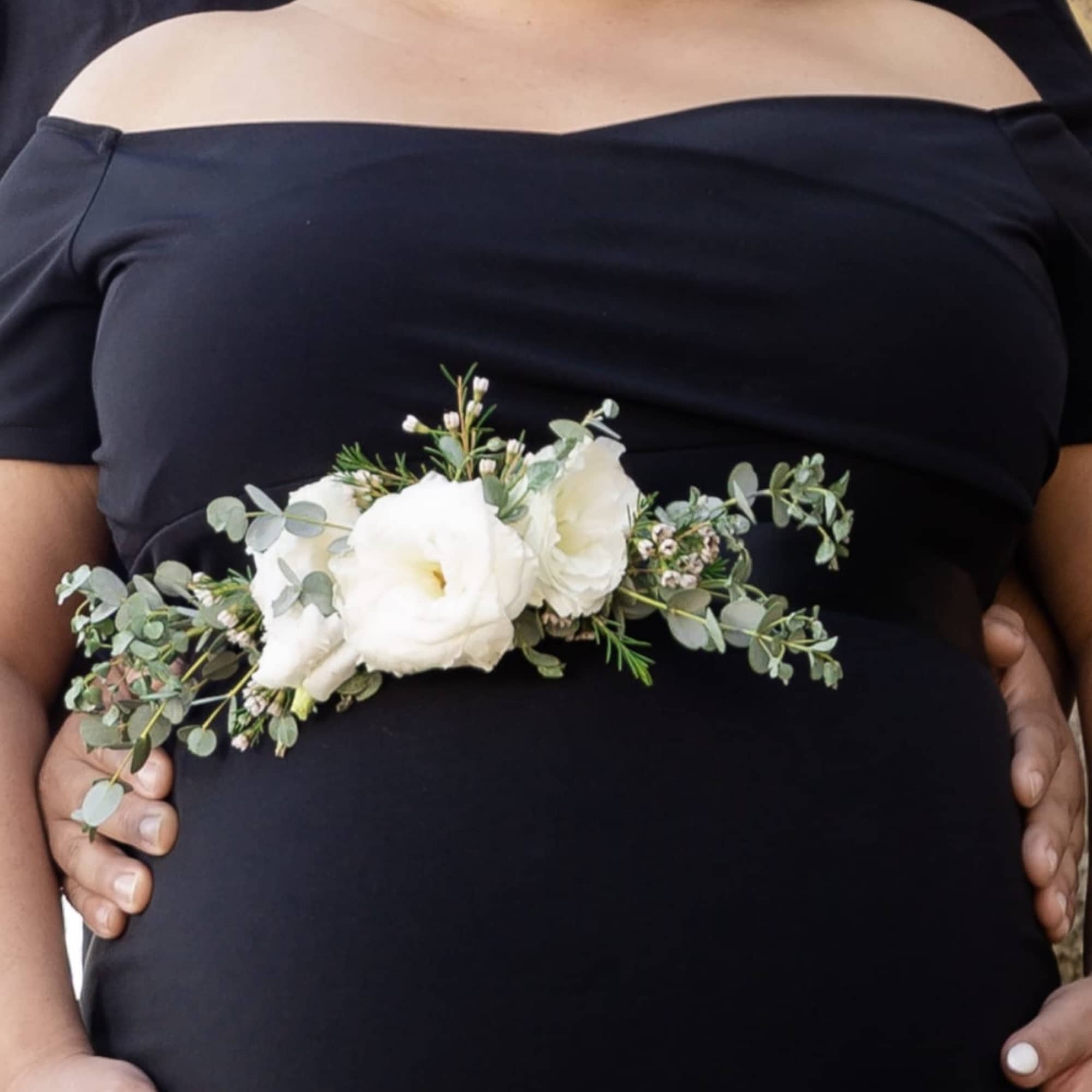 White floral corsage with greenery worn at the waist