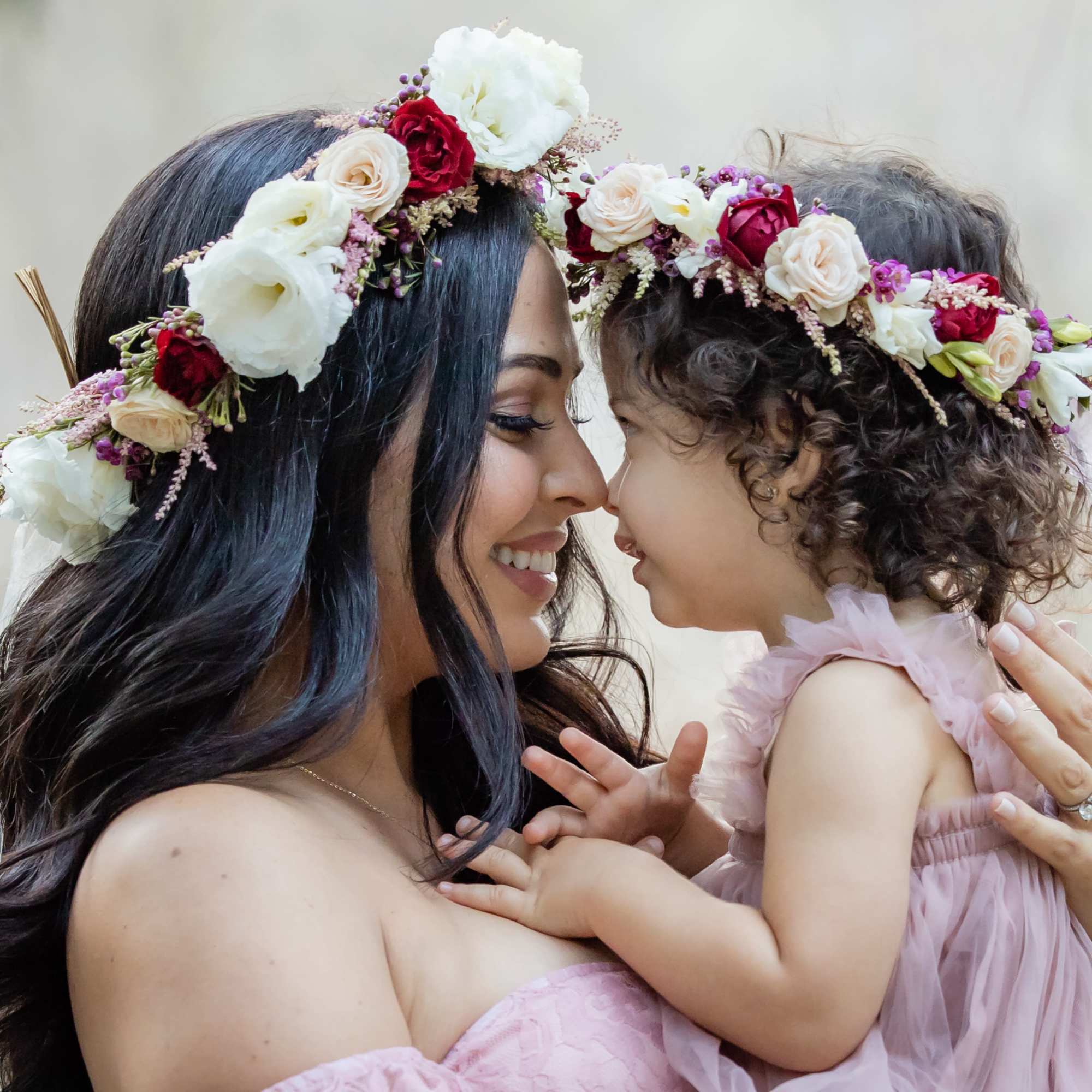 Woman and child wearing floral crowns and touching foreheads