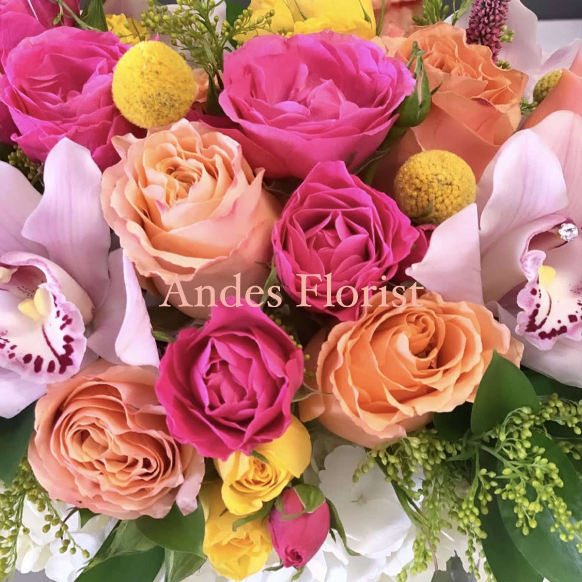 Mixed bouquet of pink, peach, yellow, and white flowers in a vase