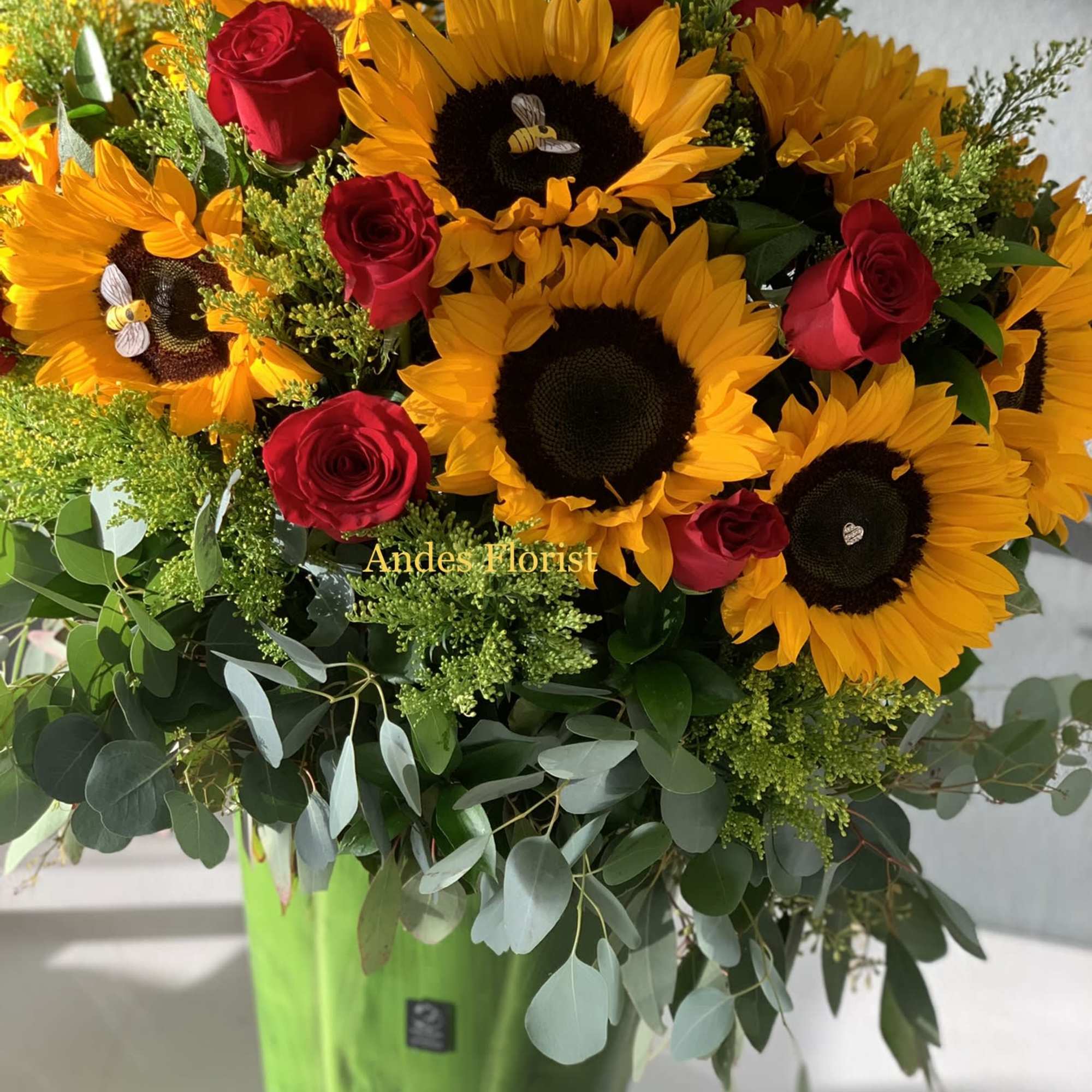 Sunflowers and red roses in a green glass vase