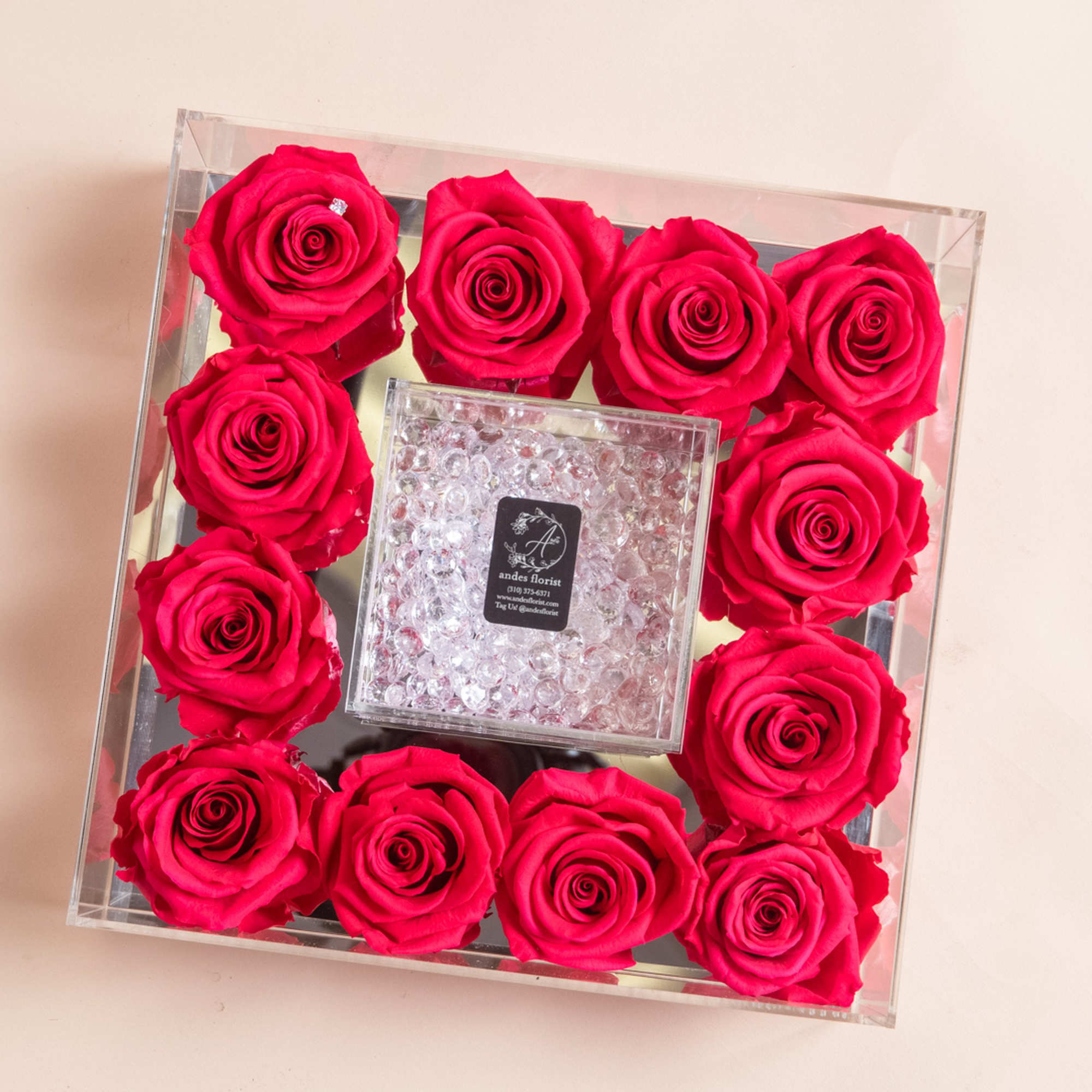 Square clear box filled with hot pink roses around a crystal center