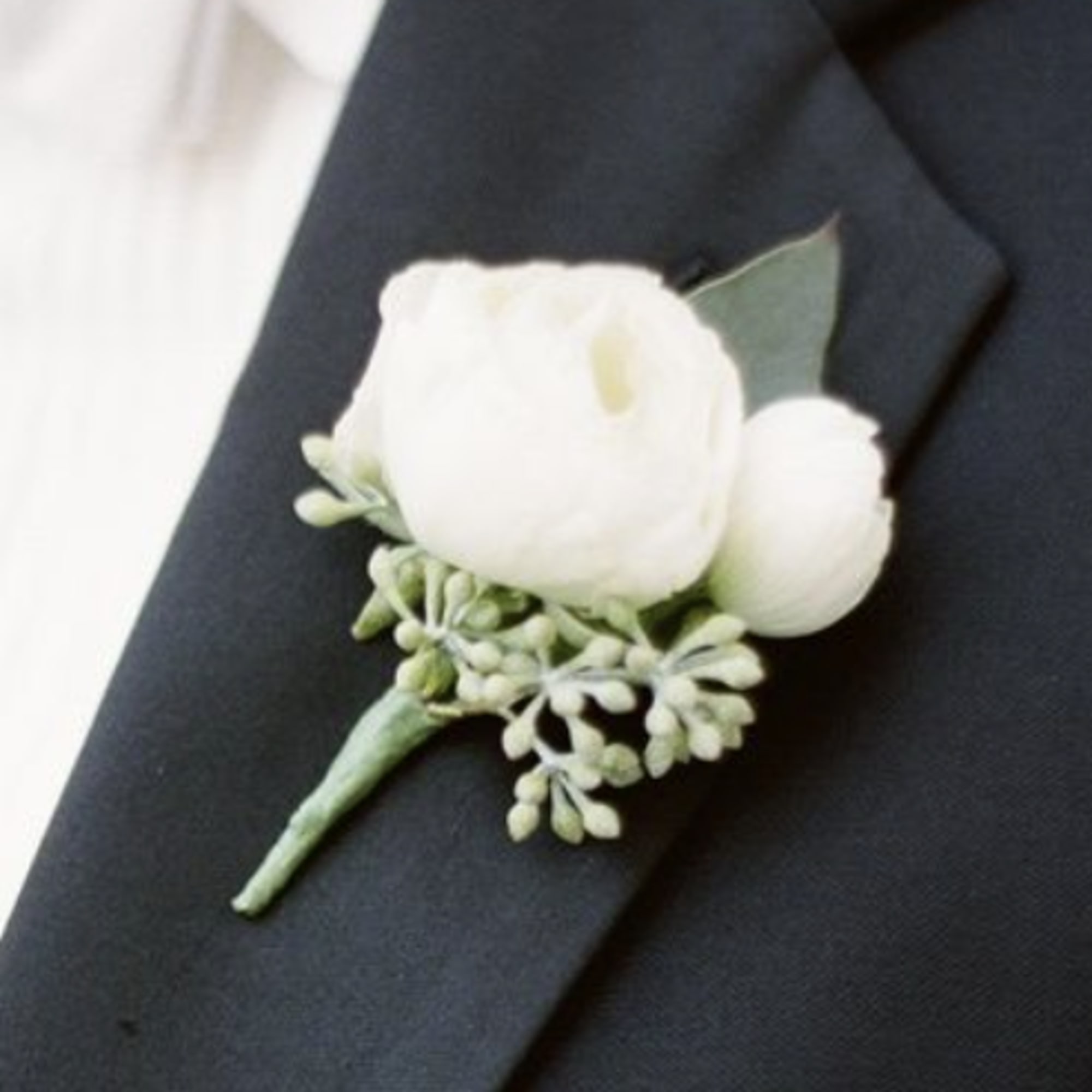 White boutonniere pinned to a dark suit lapel