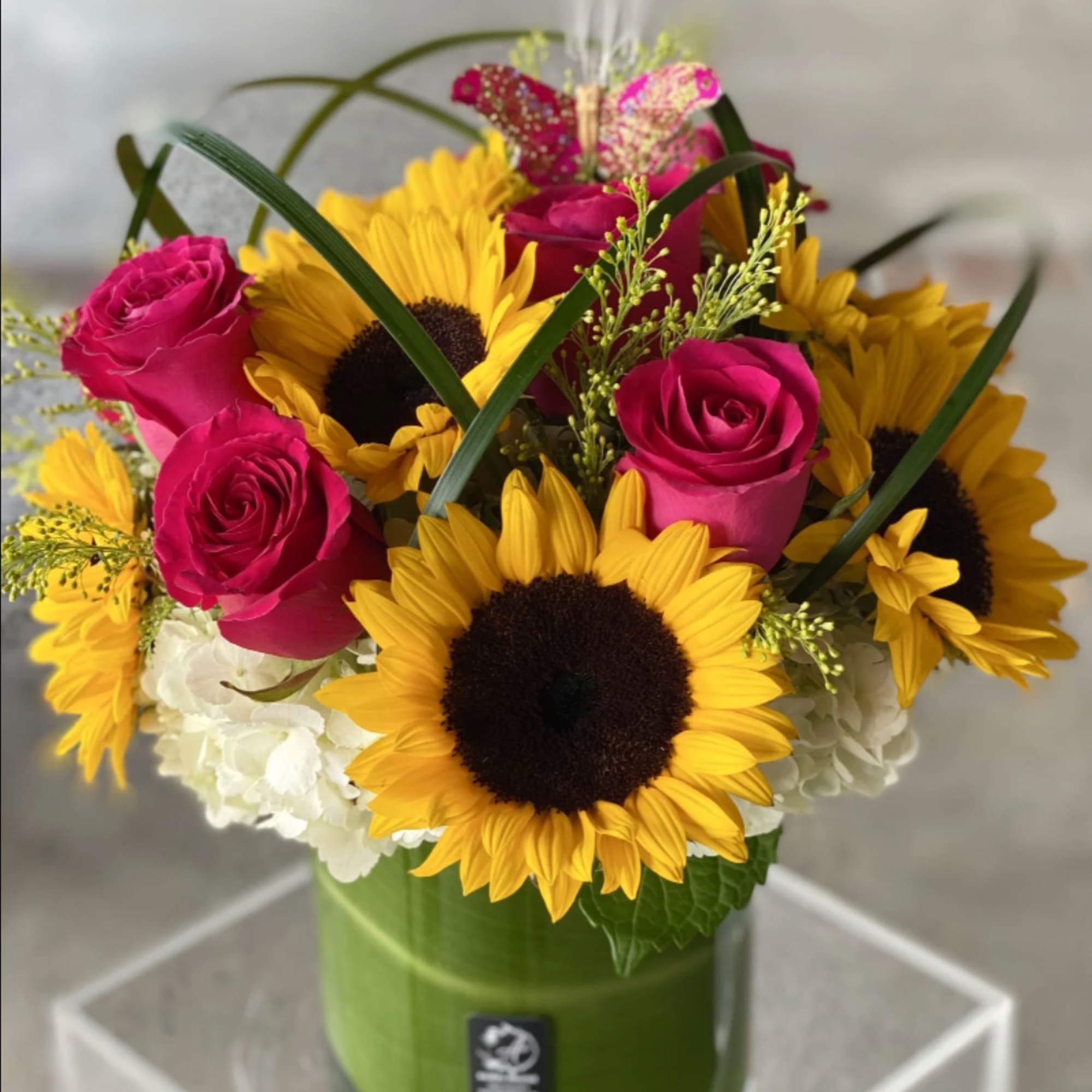 Bouquet of pink roses and yellow sunflowers in a green vase