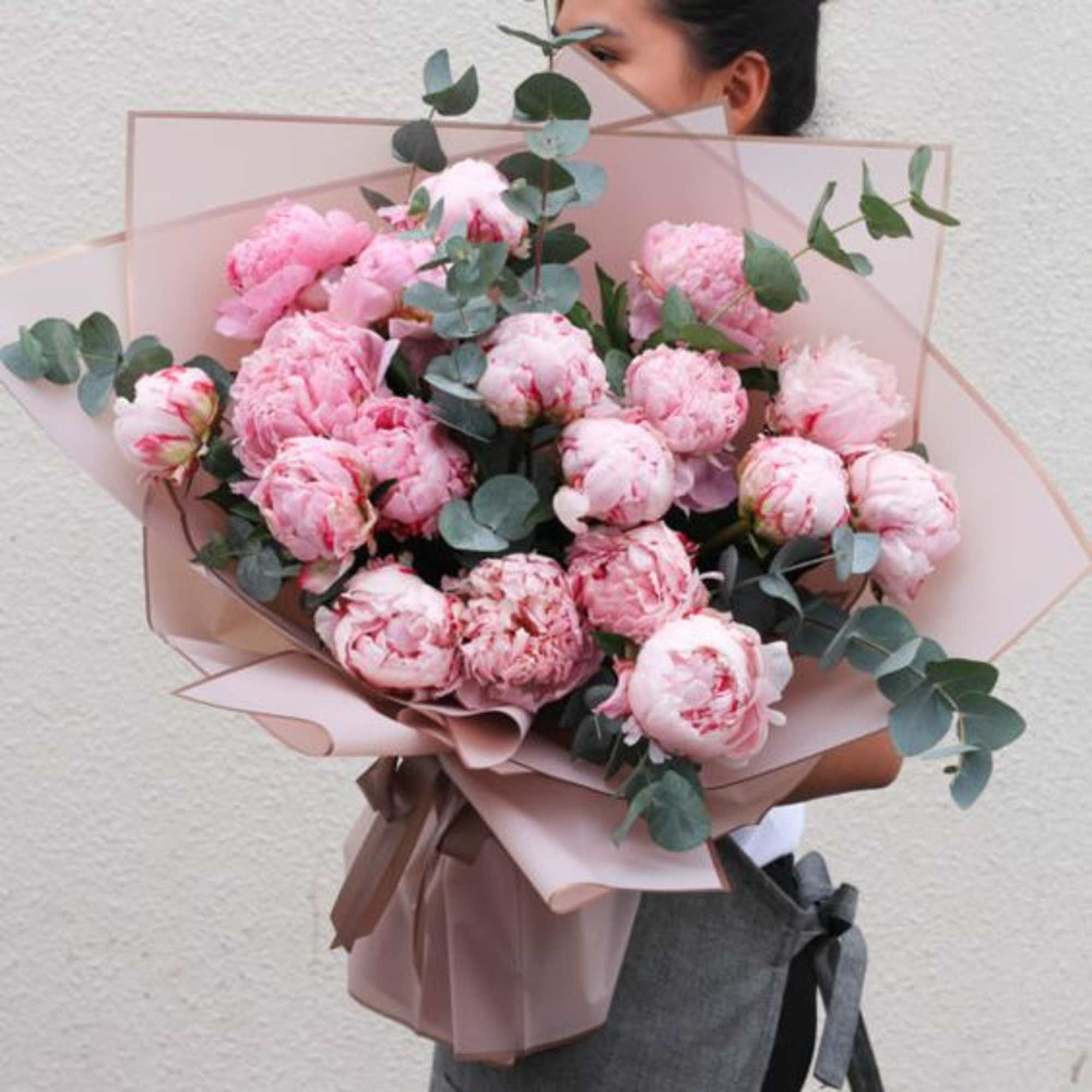 Pink peony bouquet wrapped in blush paper with eucalyptus