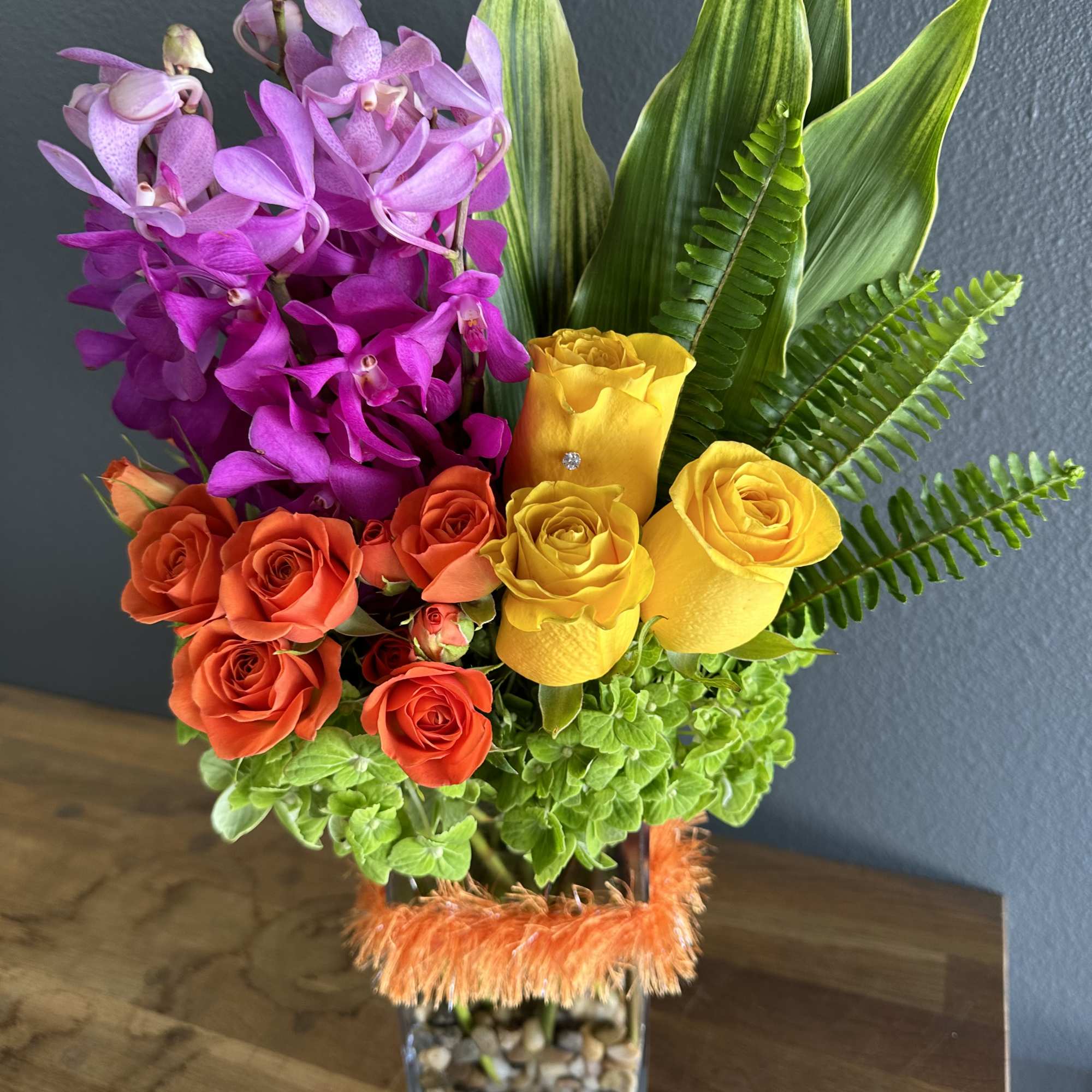 Colorful arrangement of orchids and roses in a glass vase