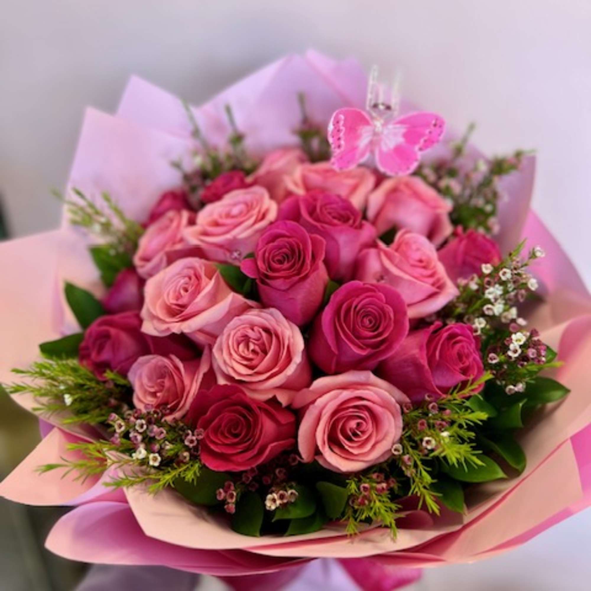 Bouquet of pink and red roses with a butterfly pick