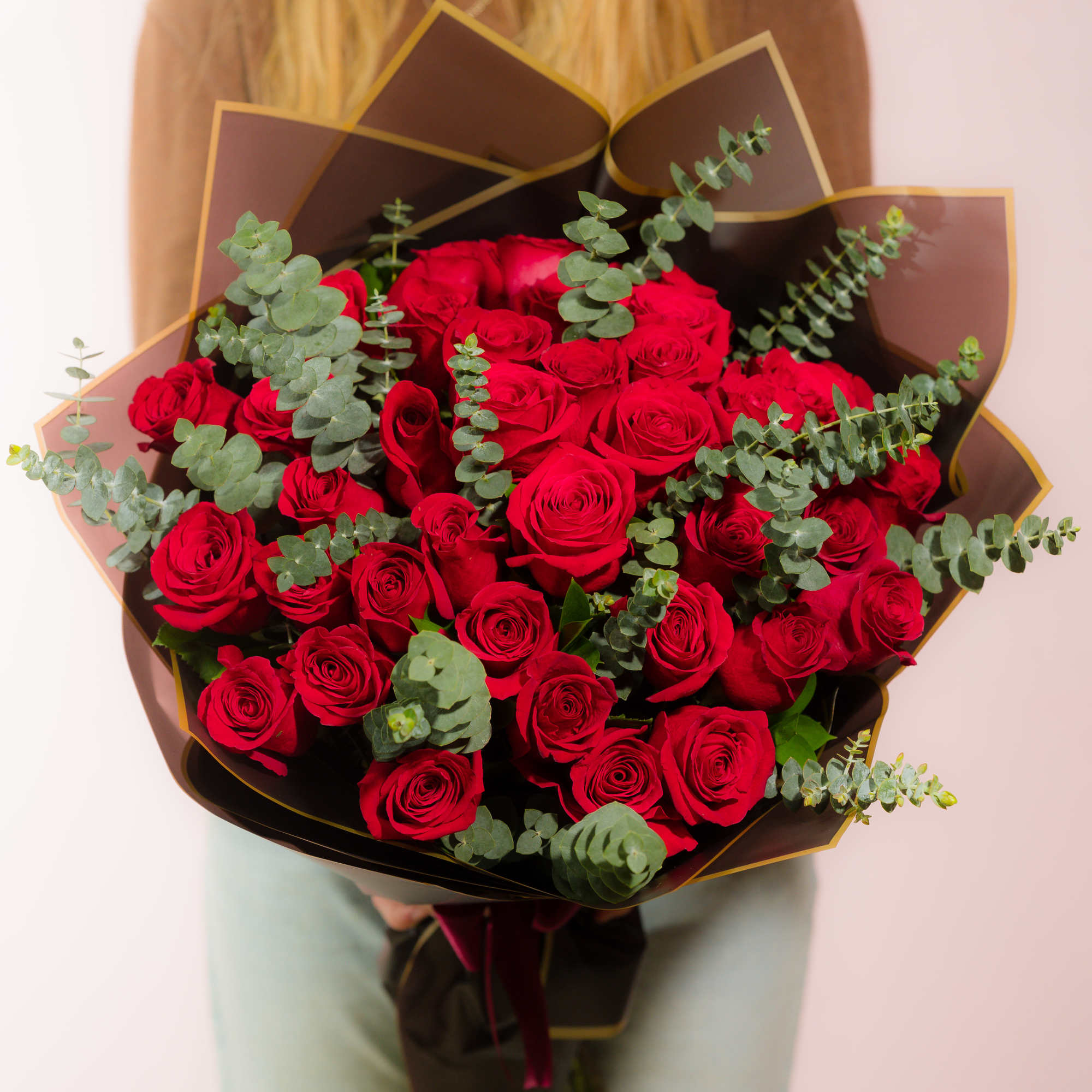 Large bouquet of red roses with eucalyptus in dark wrap