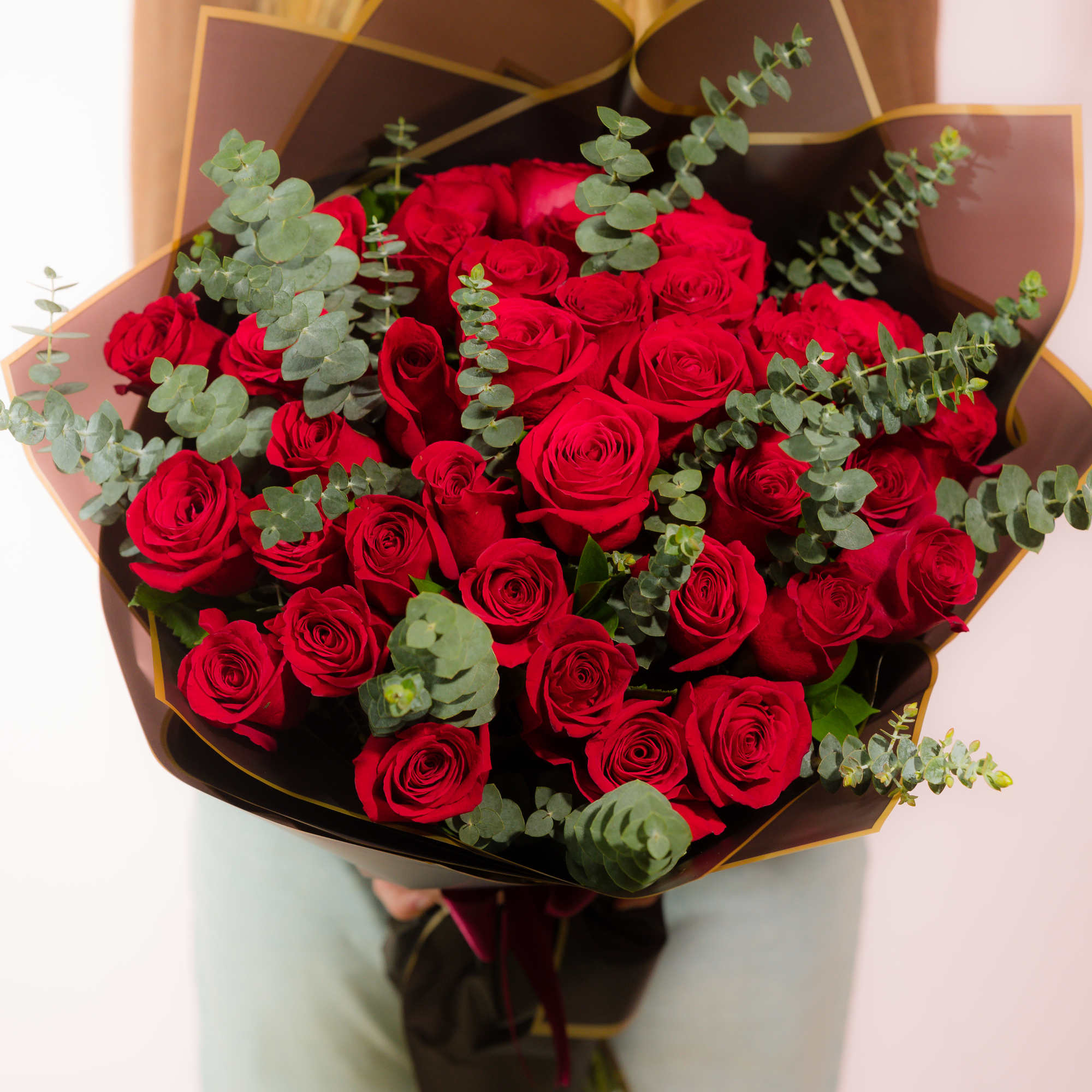 Bouquet of red roses with eucalyptus in dark wrap