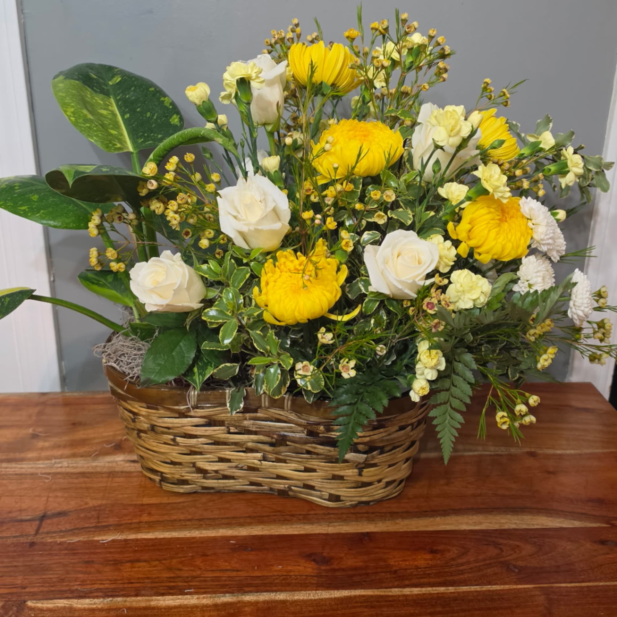 Yellow and white floral arrangement in a woven basket