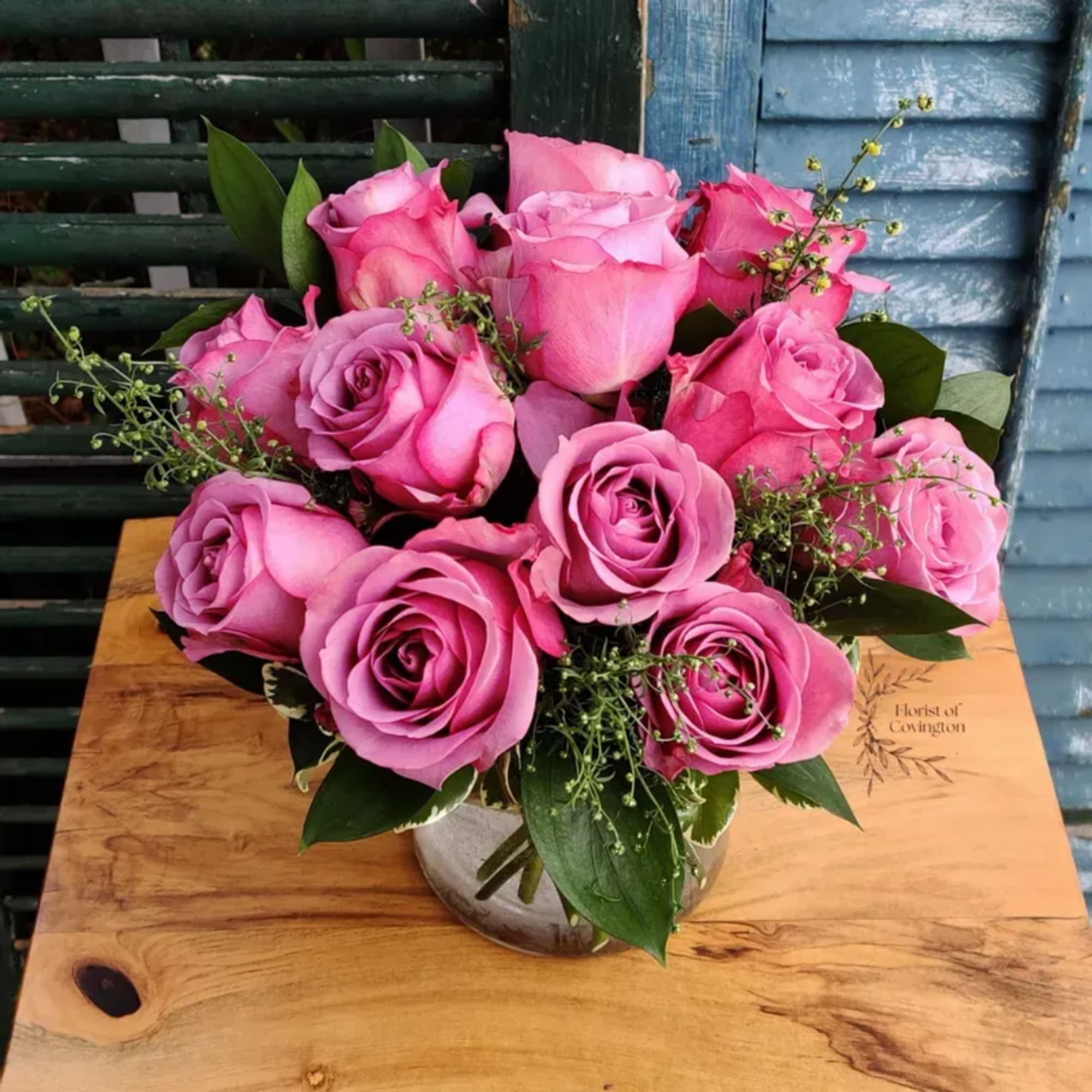 Pink roses arranged in a clear glass vase with greenery