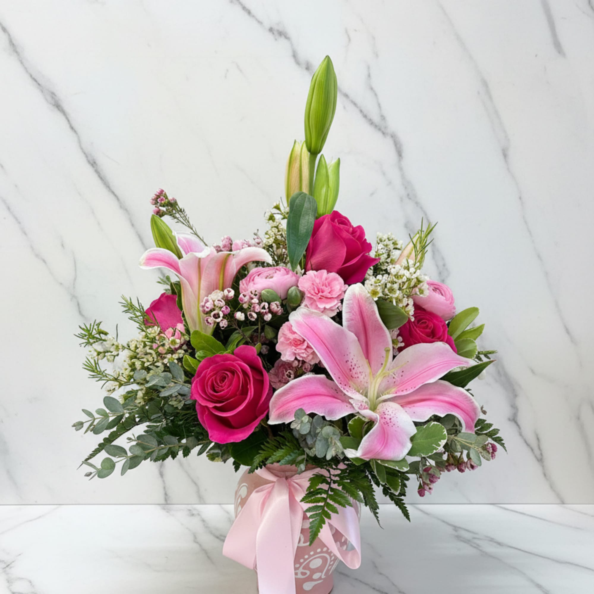 A vibrant arrangement of hot pink roses, soft light pink lilies, carnations
