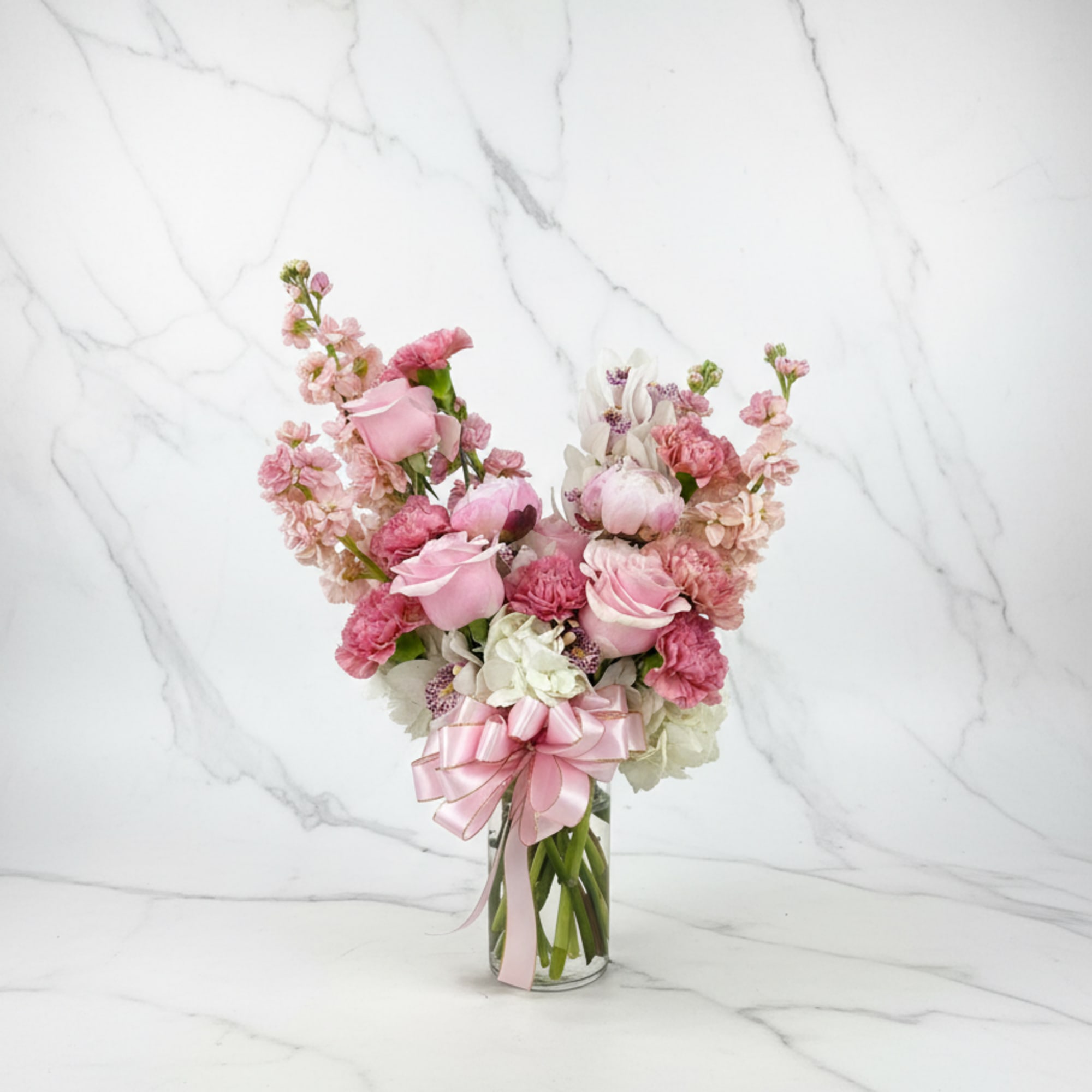 A soft and elegant vase arrangement featuring white hydrangea, peach stock, lege