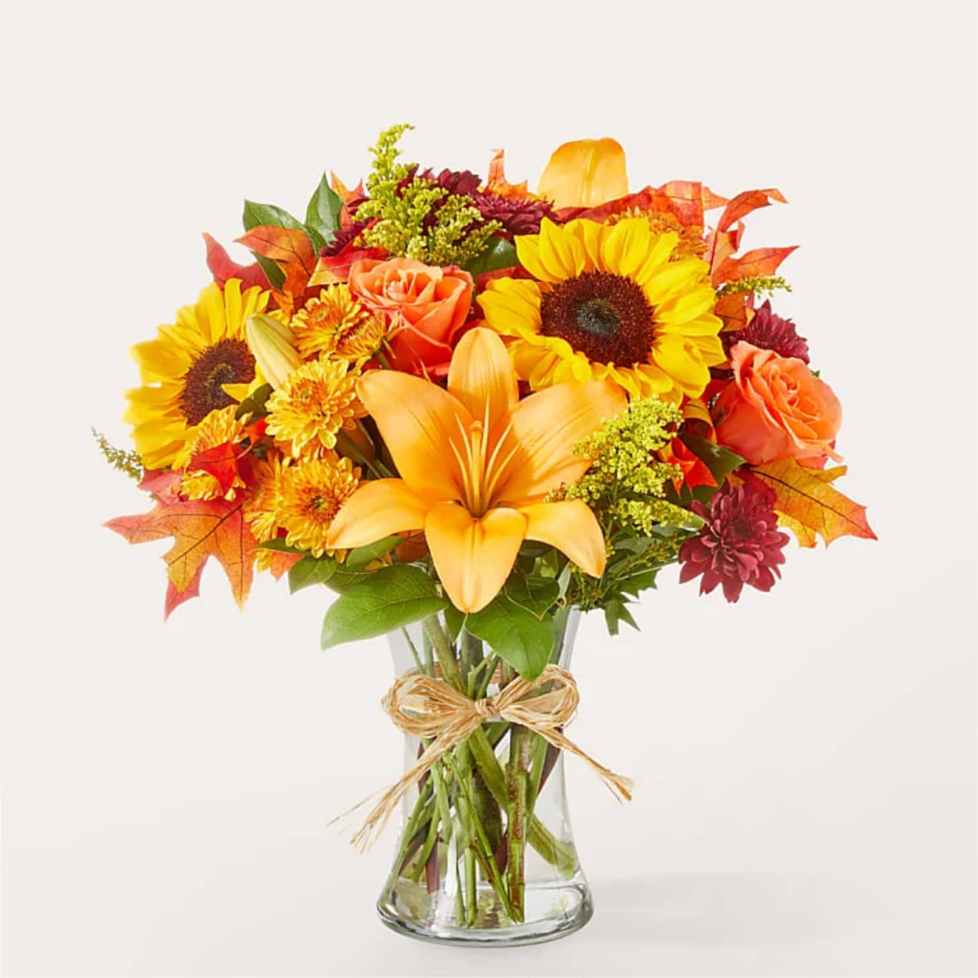Bouquet of sunflowers, lilies, and roses in a clear glass vase