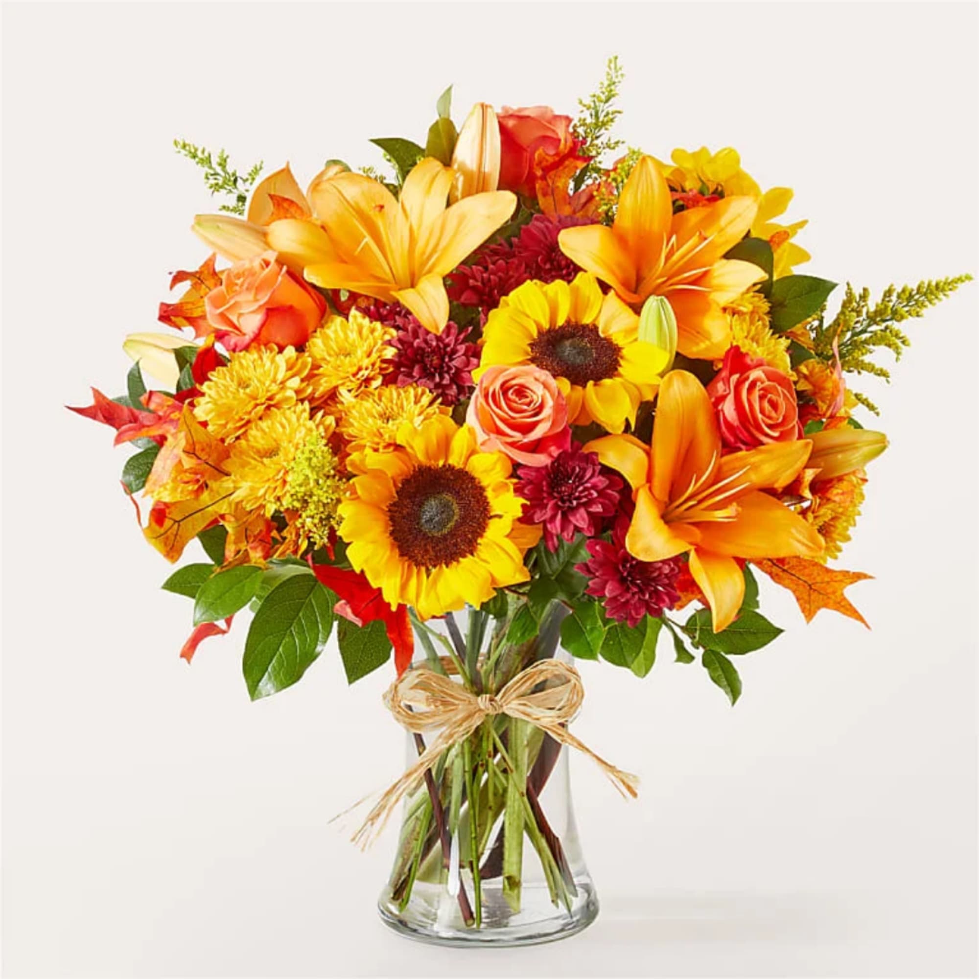 Autumn bouquet of sunflowers, lilies, roses, and mums in a glass vase