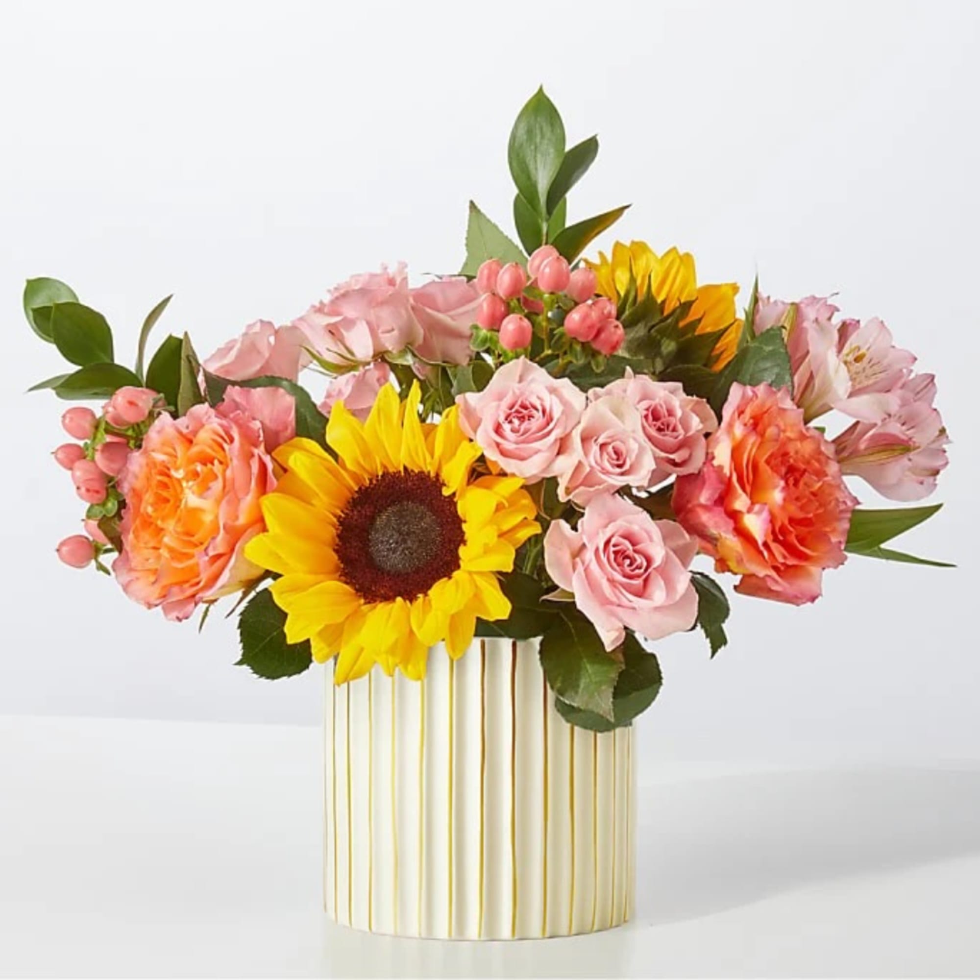 Pink roses and sunflowers arranged in a striped vase