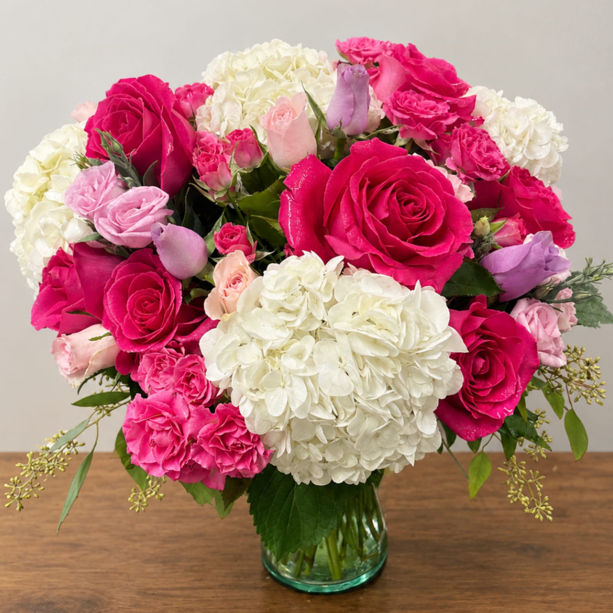 Pink roses and white hydrangeas arranged in a glass vase