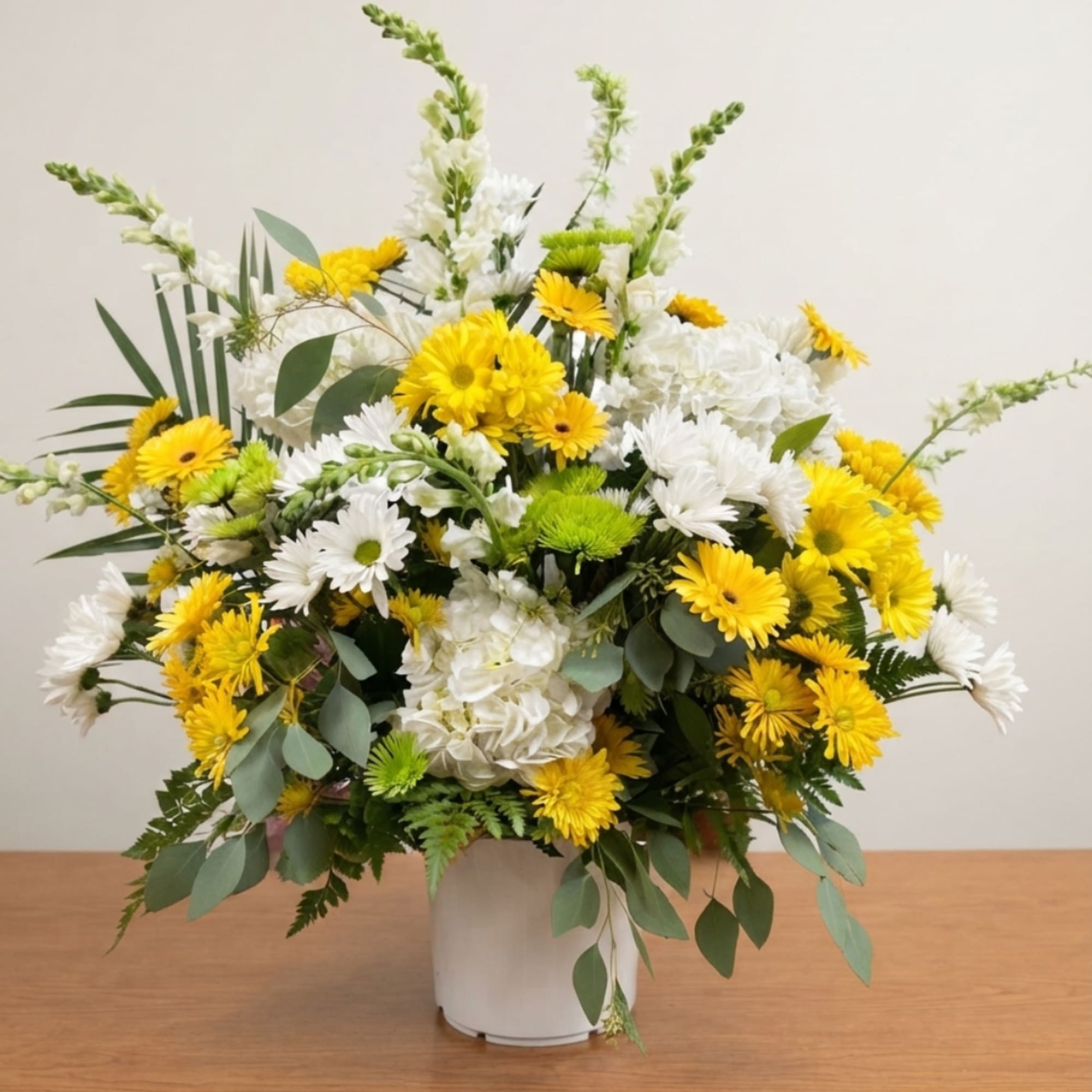 Yellow and white mixed flower arrangement in a white vase