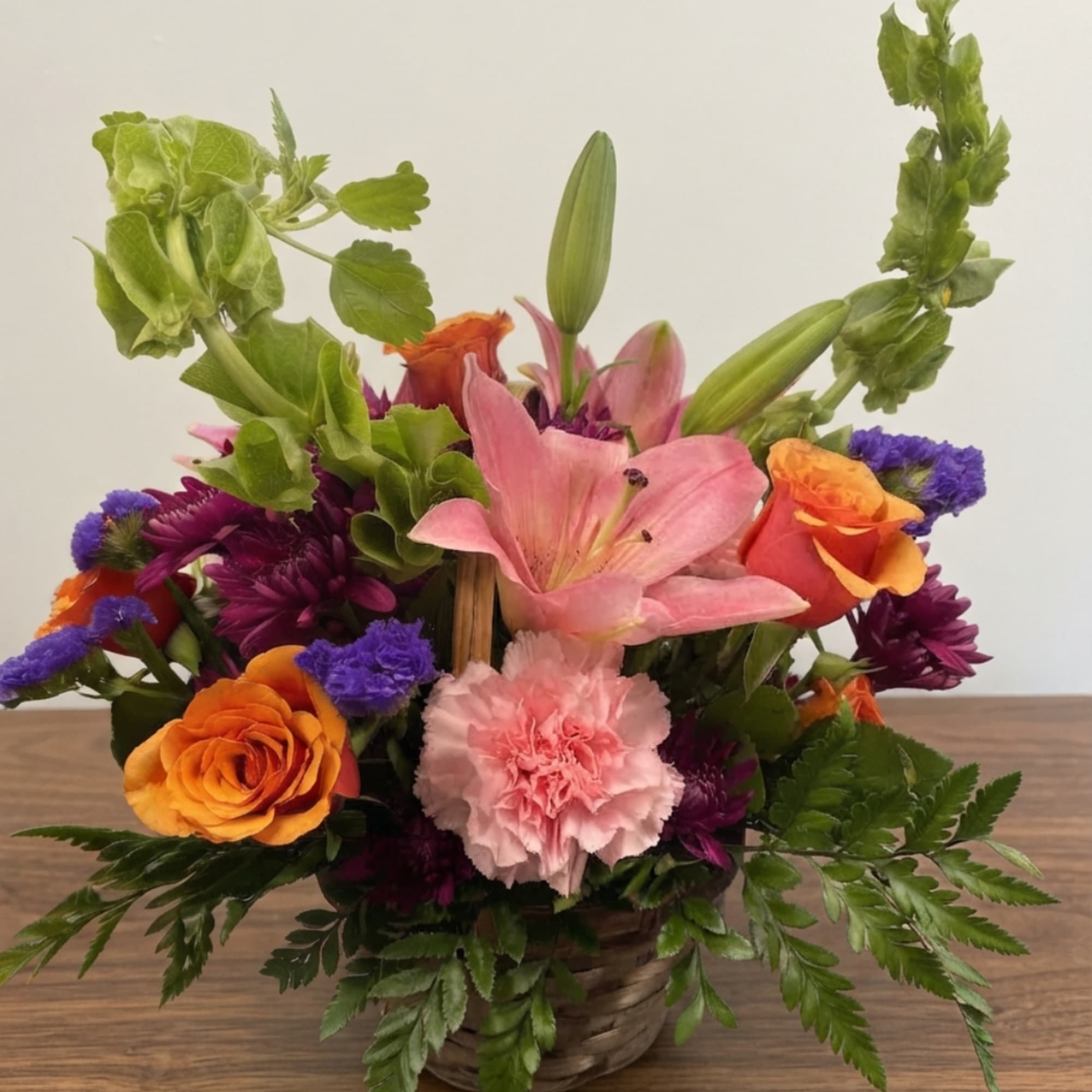 Colorful mixed flower arrangement in a woven basket with lilies and roses