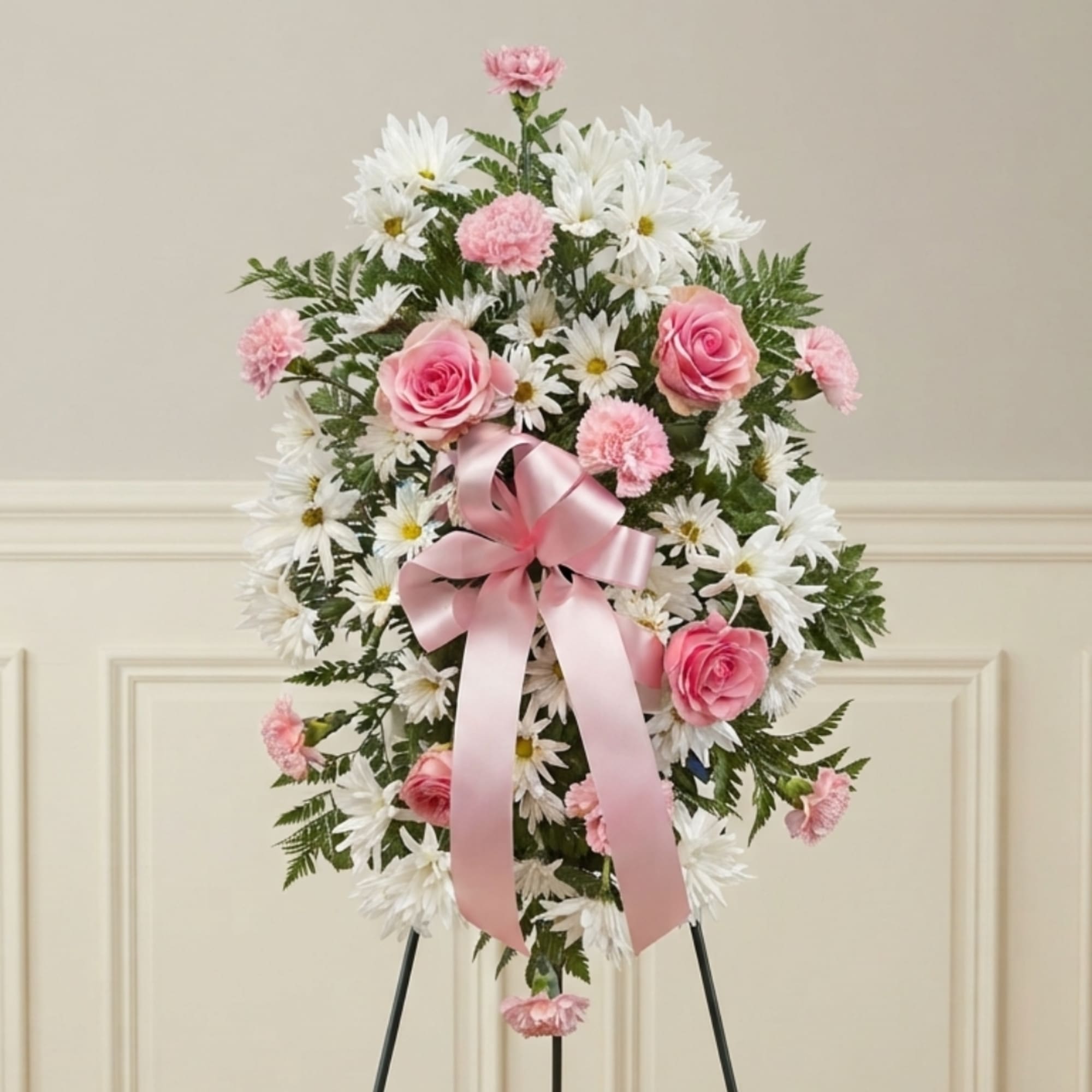 Pink roses and carnations with white daisies on a standing easel spray with a pink ribbon