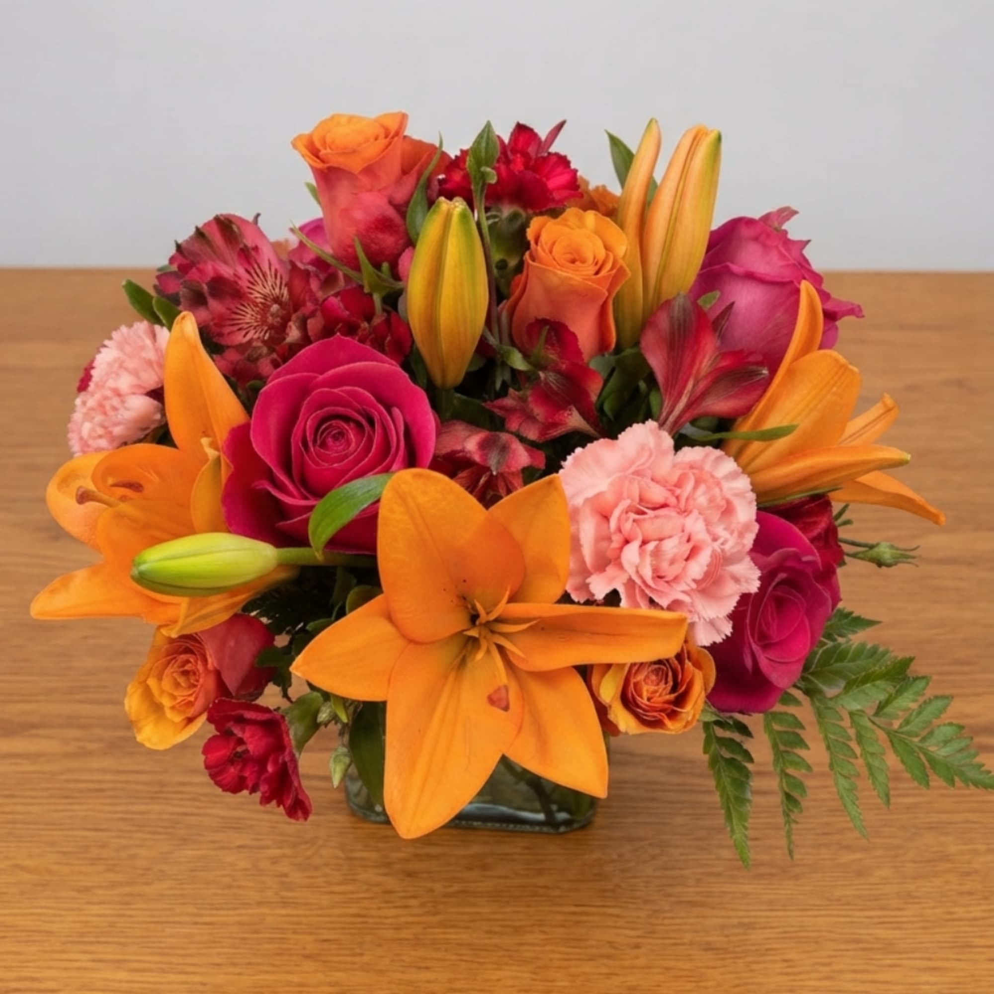 Bouquet of orange lilies, pink roses, and carnations in a glass vase