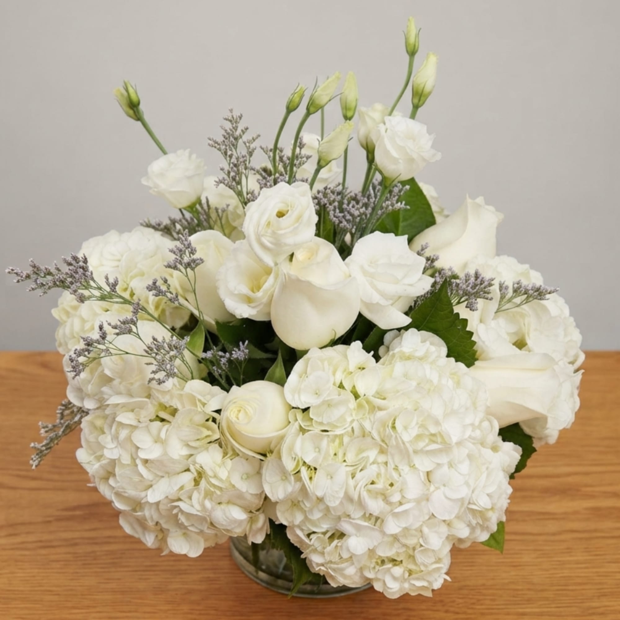 White roses and hydrangeas arranged in a glass vase