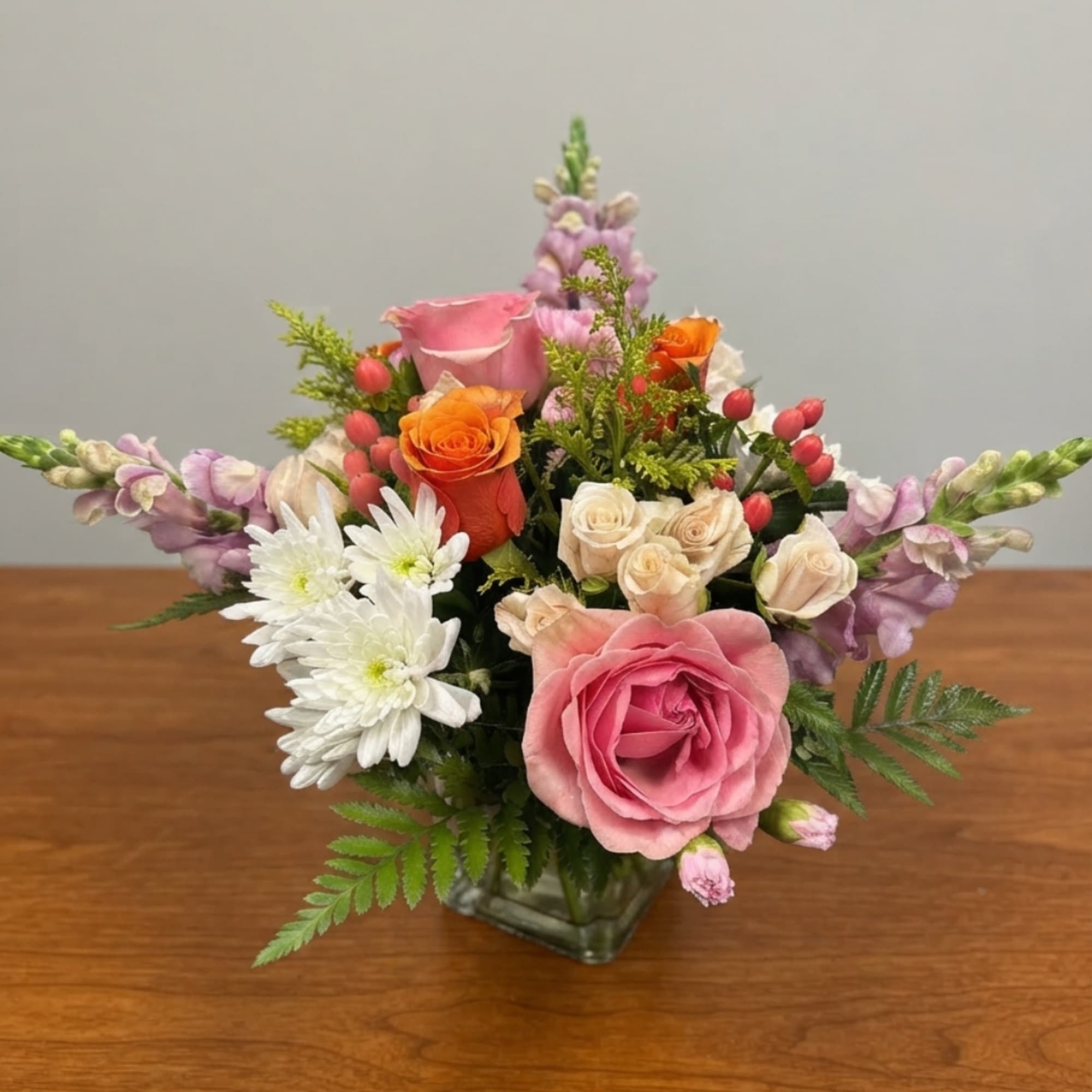 Mixed bouquet of pink, orange, and white flowers in a glass vase