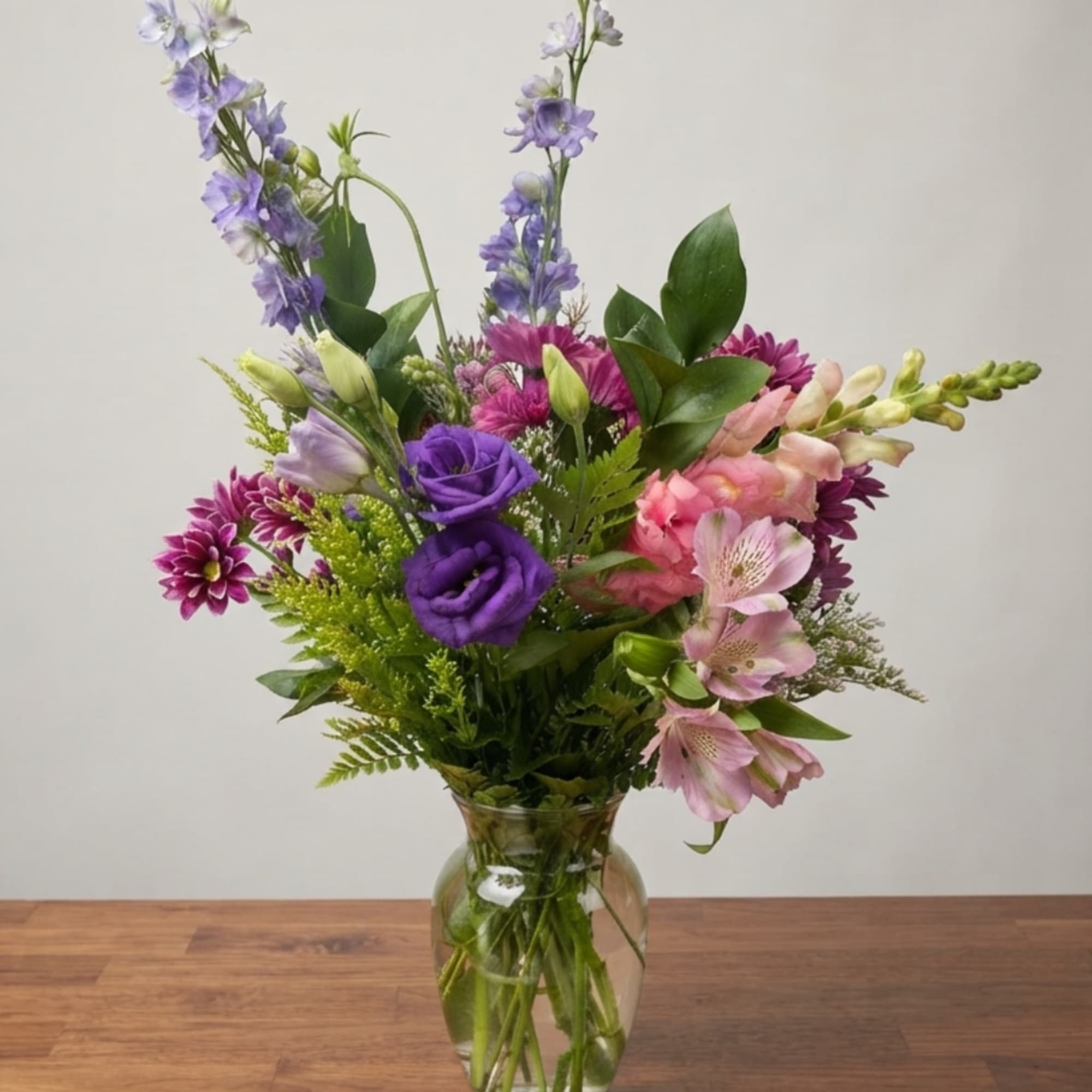 Mixed bouquet of purple, pink, and white flowers in a glass vase