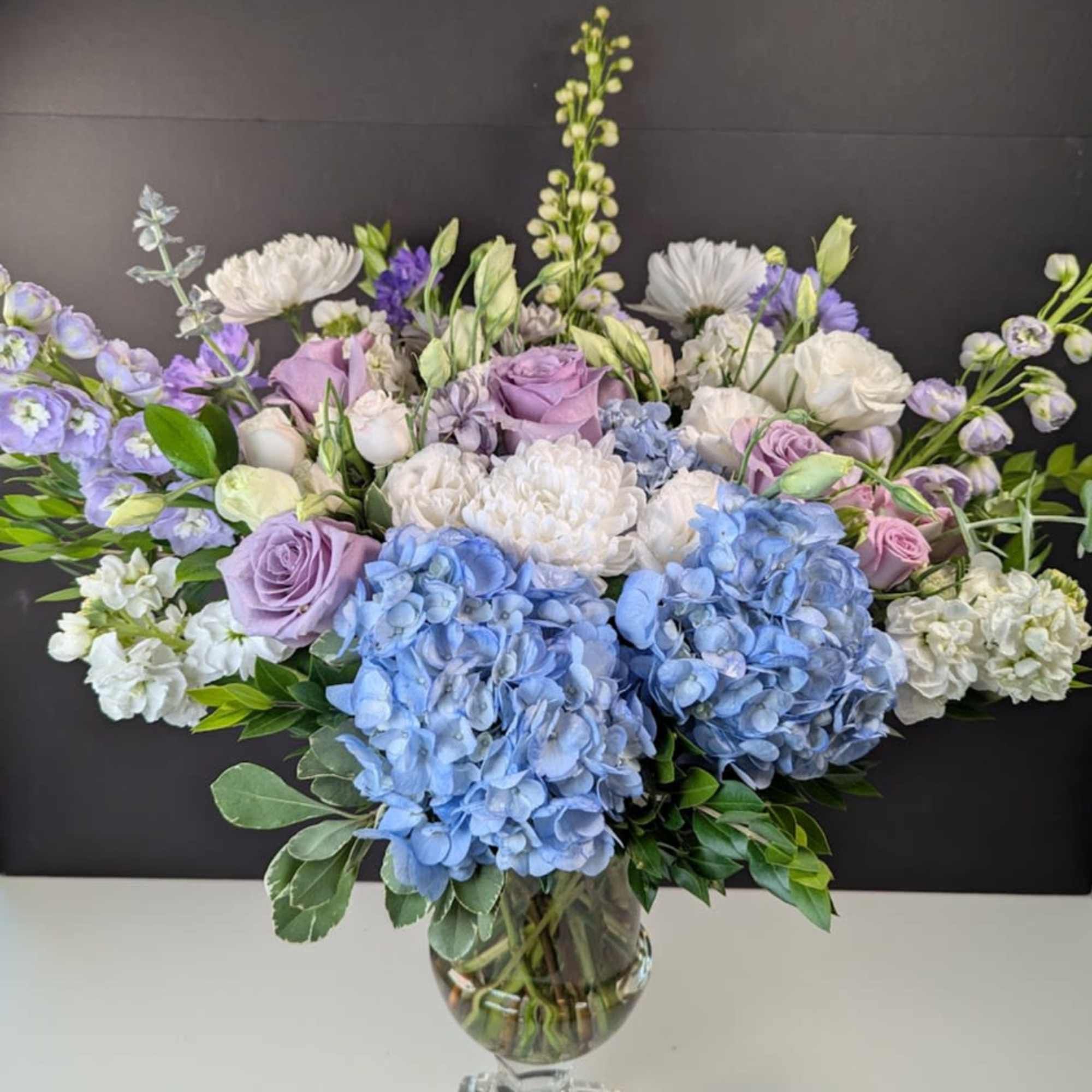 Lavender and blue floral arrangement in a clear glass vase