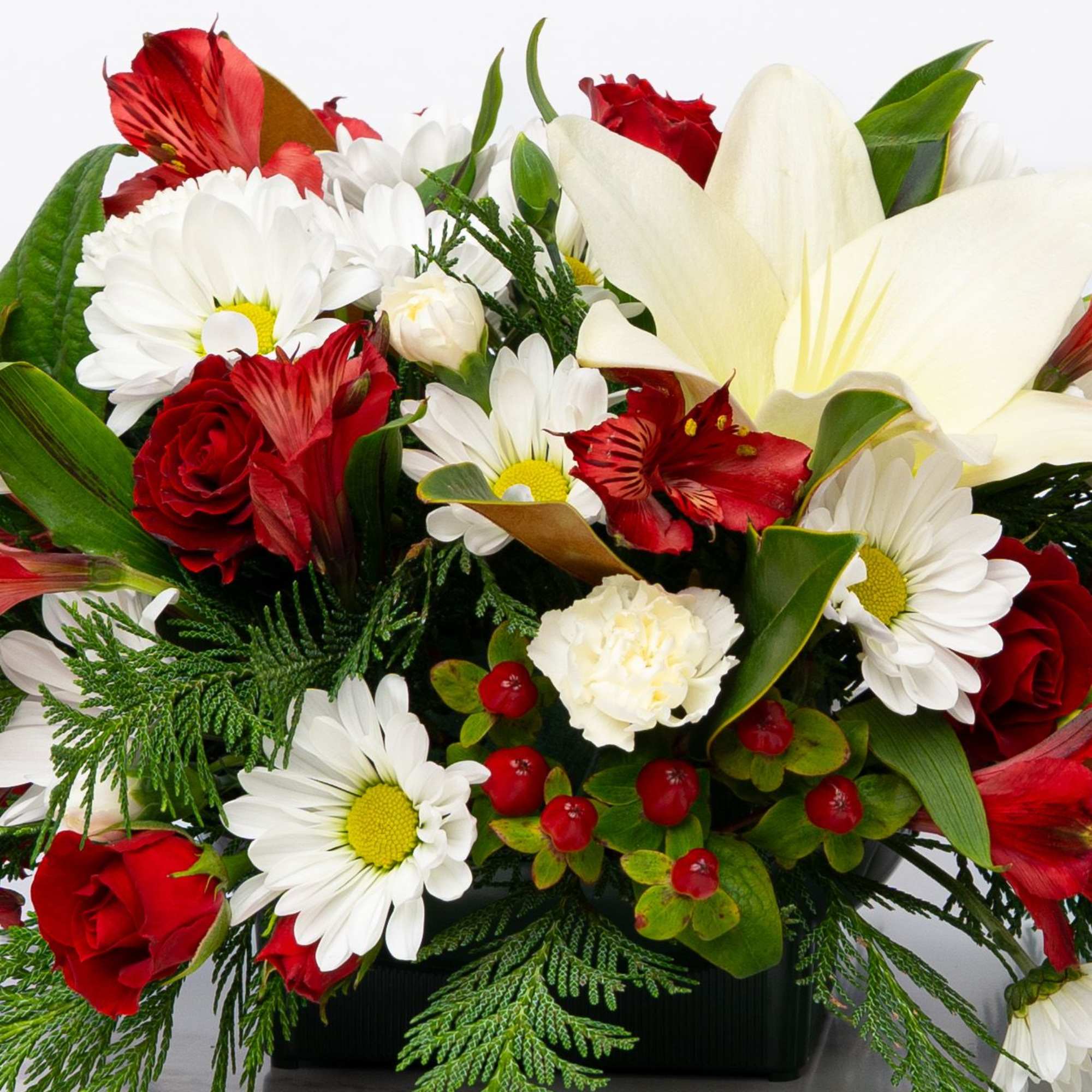 Red roses and white daisies arranged with a large white lily in a black container